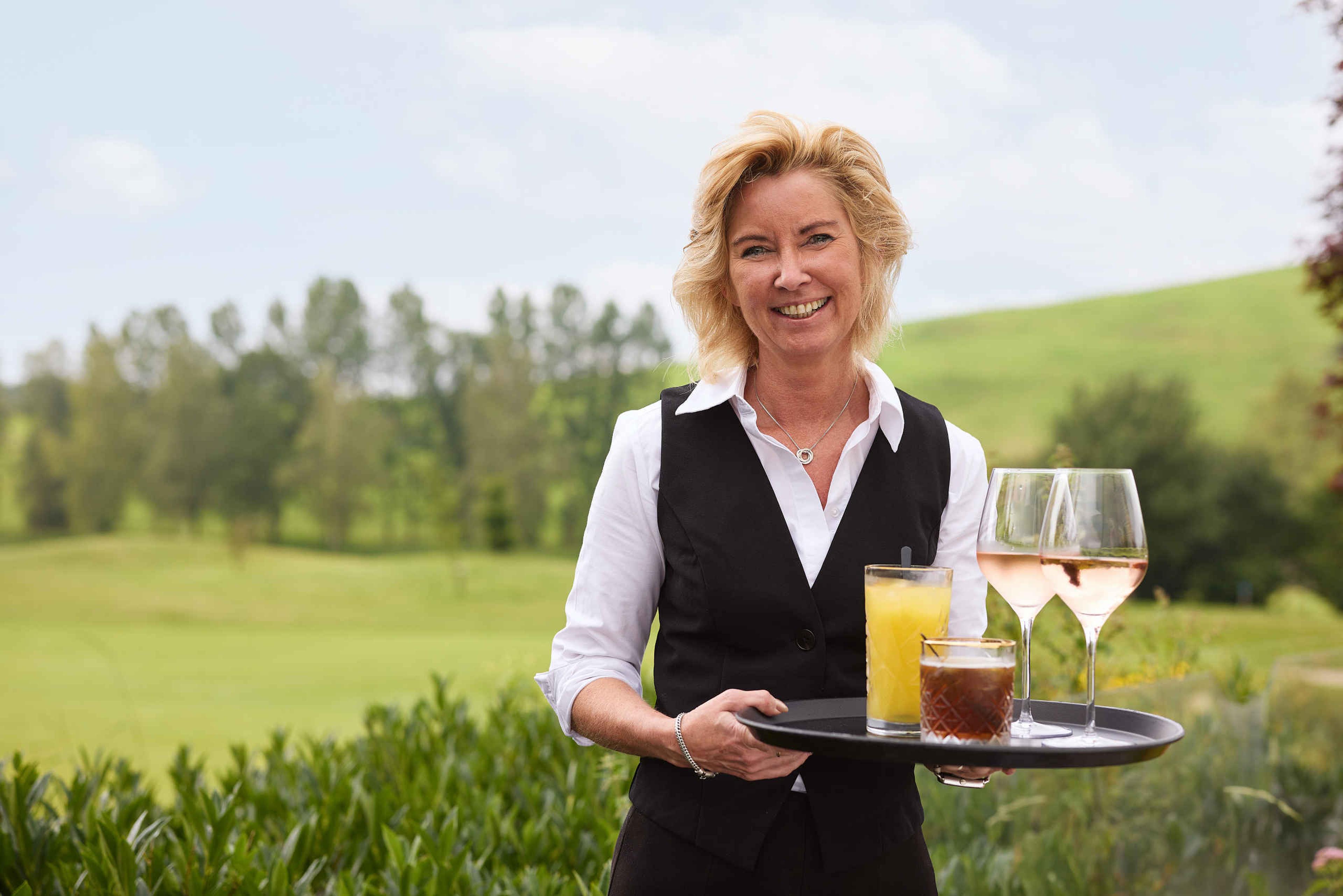 Medewerkster bediening met drankjes bij restaurant De hooghe Bergh bij Golf de Gulbergen