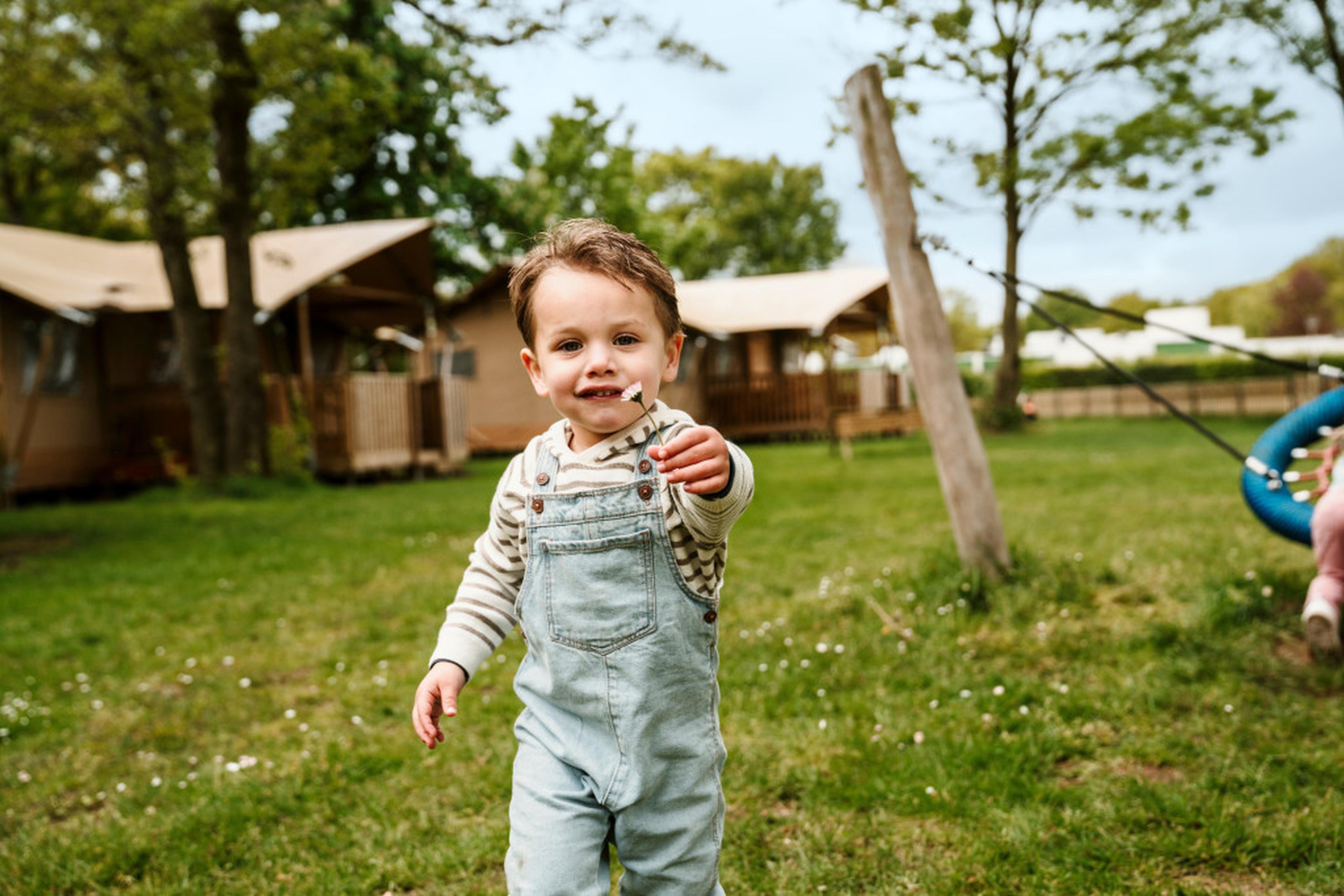 Een jongen met een bloemetje in de bloemenweide bij Vakantiepark Dierenbos