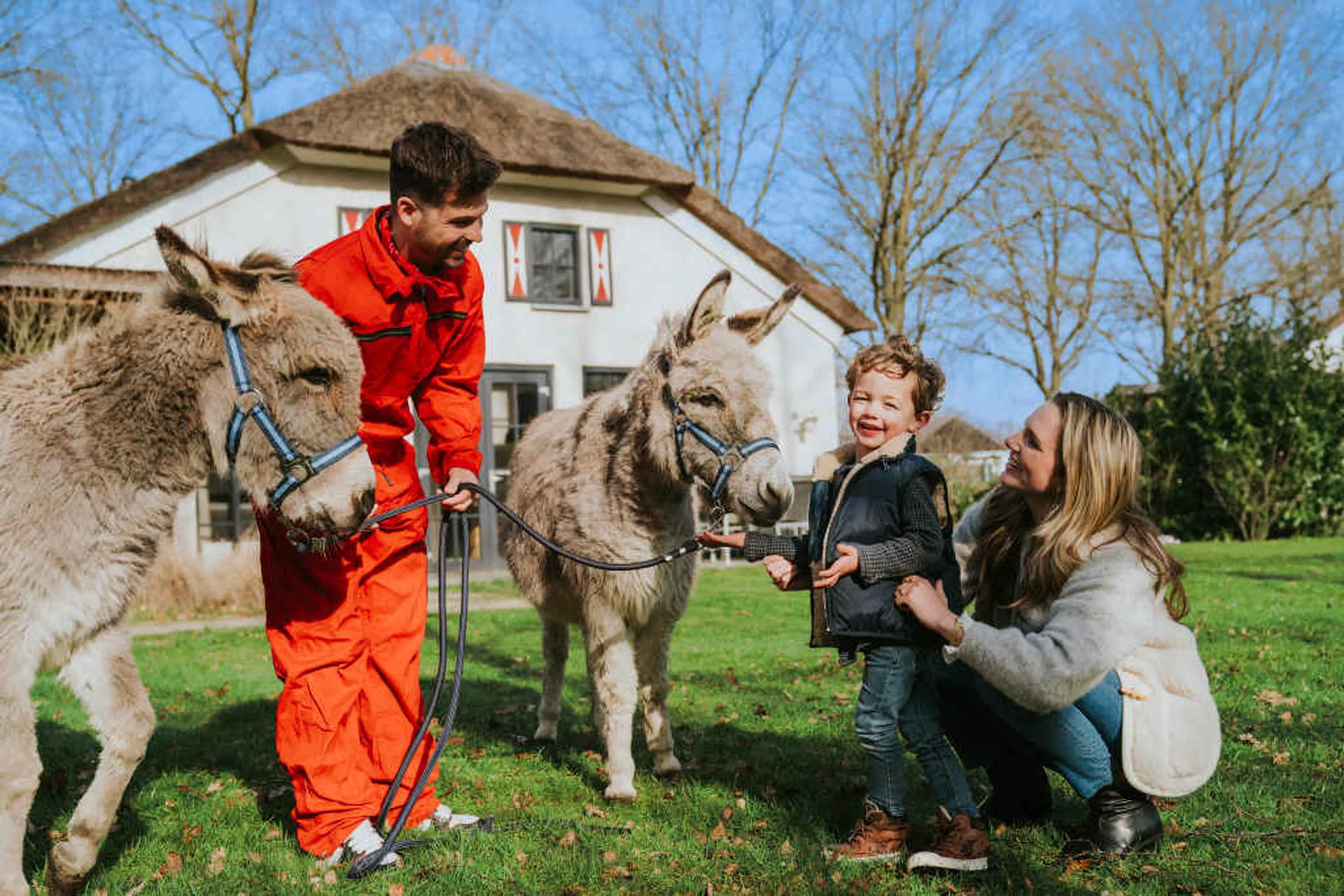 Een jongen en zijn moeder bekijken de ezels met de dierenverzorger bij Vakantiepark Dierenbos