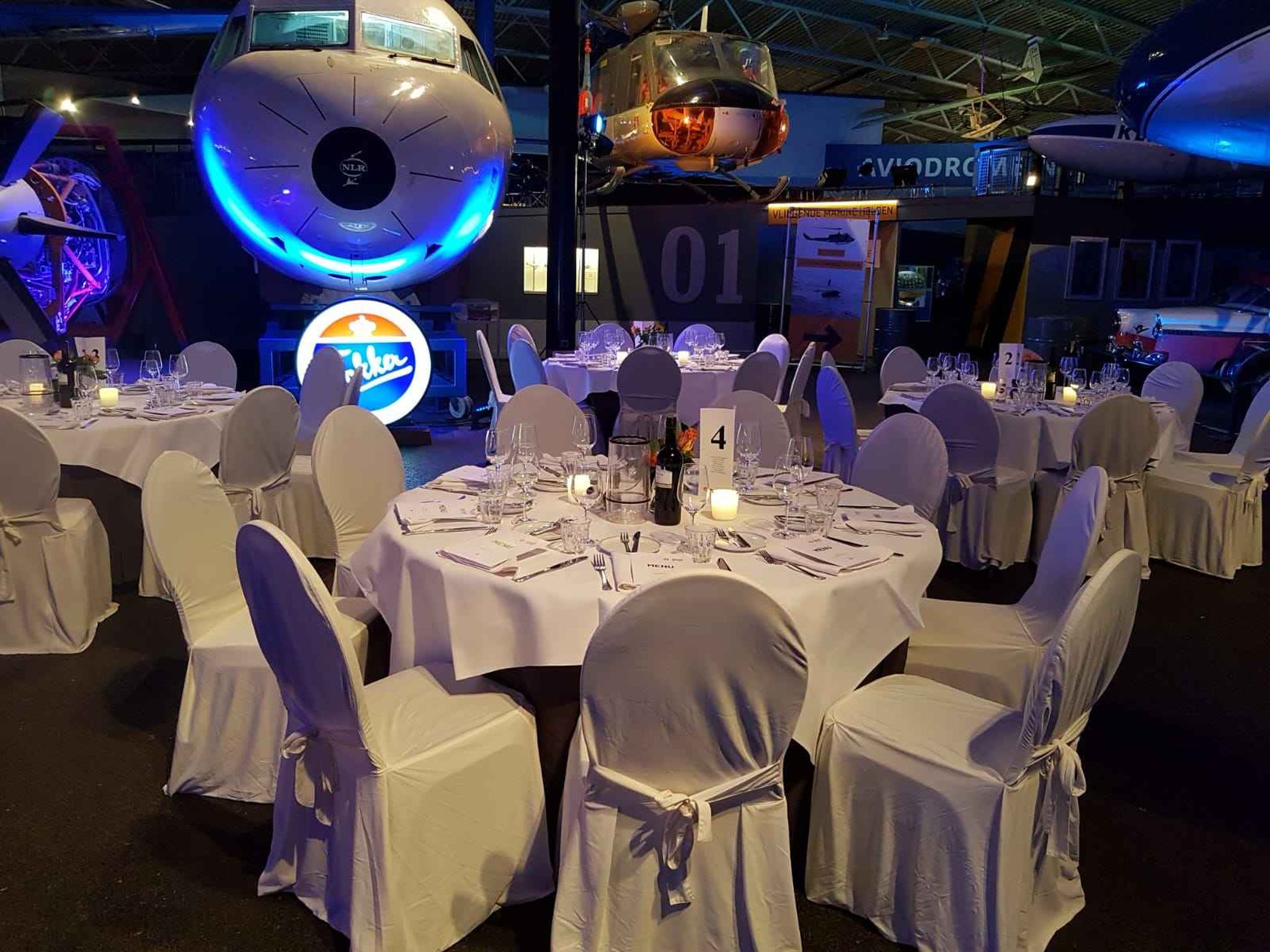De opstelling van een evenement met diner in de museumzaal van Aviodrome