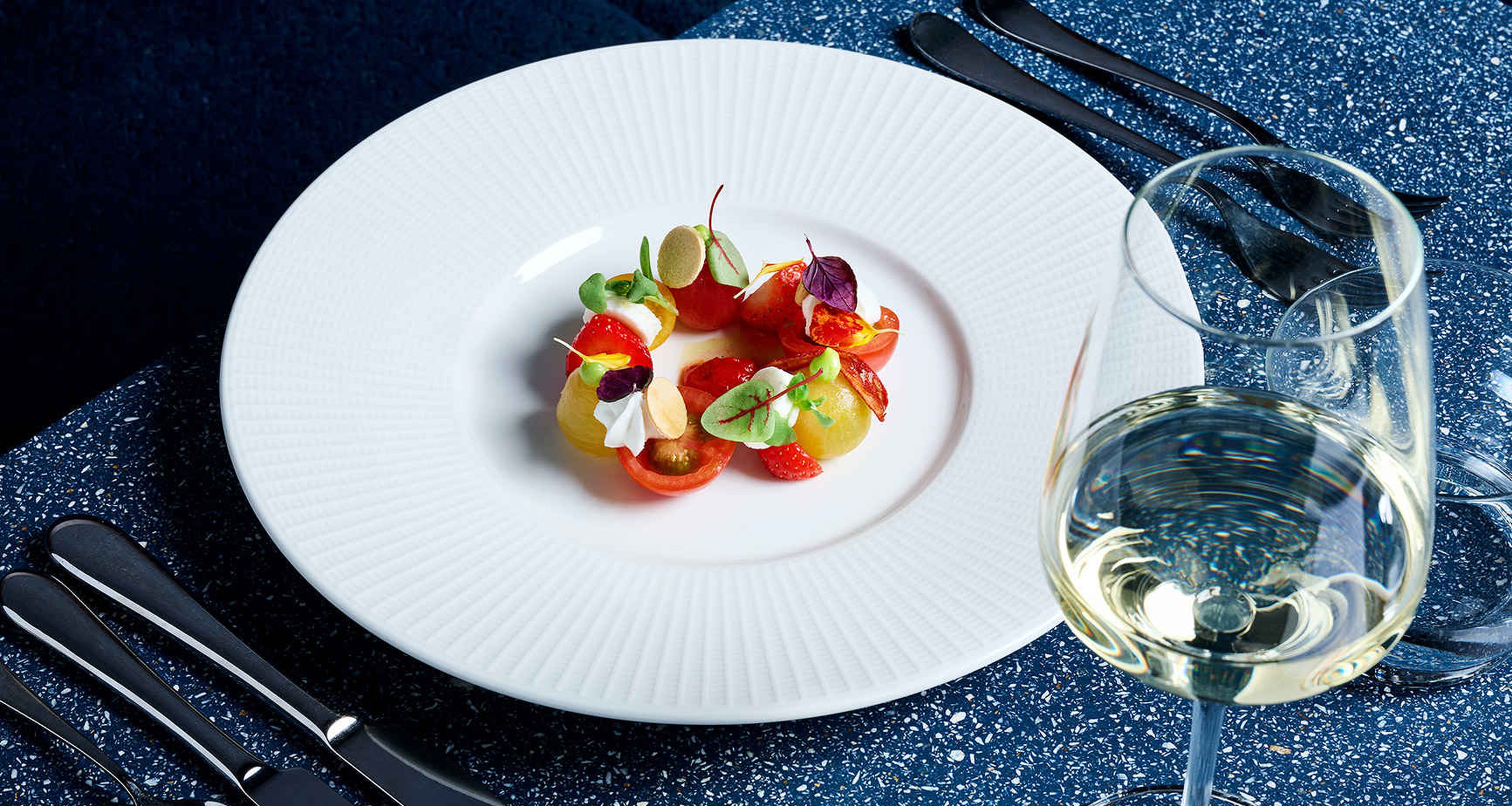 Een gerecht met een glas witte wijn op tafel bij restaurant Nommos.