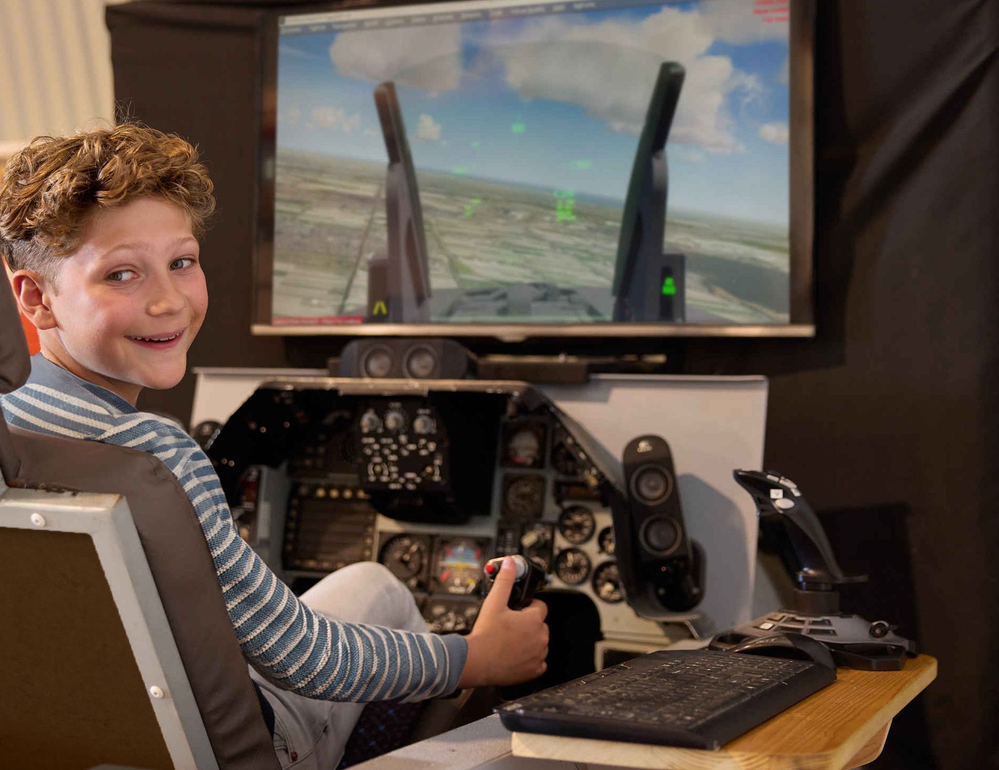 Een kind zit in de straaljager simulator bij Luchtvaartmuseum Aviodrome