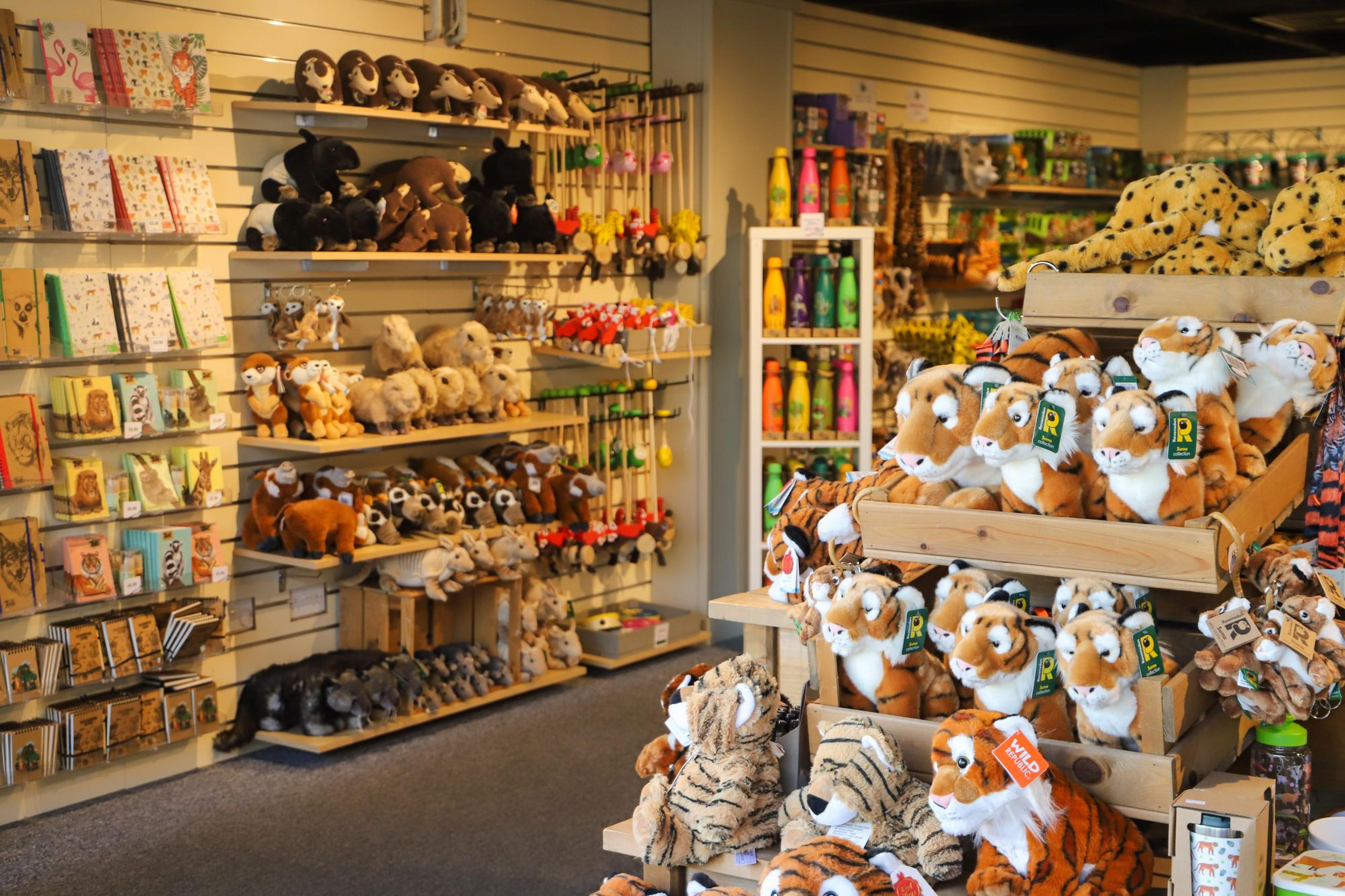 Gift shop interior with shelves of plush toys, cards, and souvenirs. Stuffed animals, including tigers and leopards, prominently displayed.