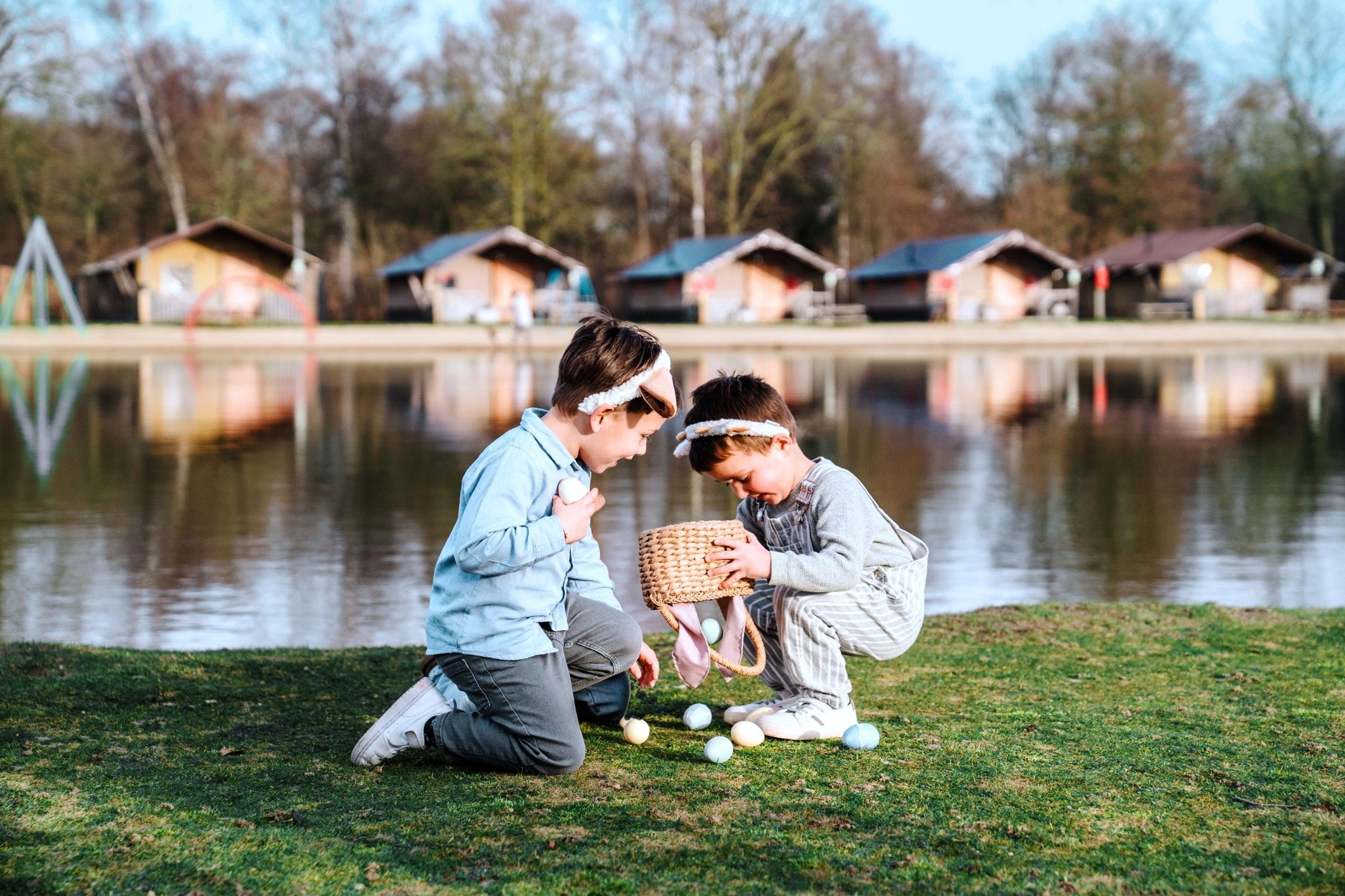 Twee kinderen zoeken paaseieren tijdens Pasen bij Vakantiepark Dierenbos.