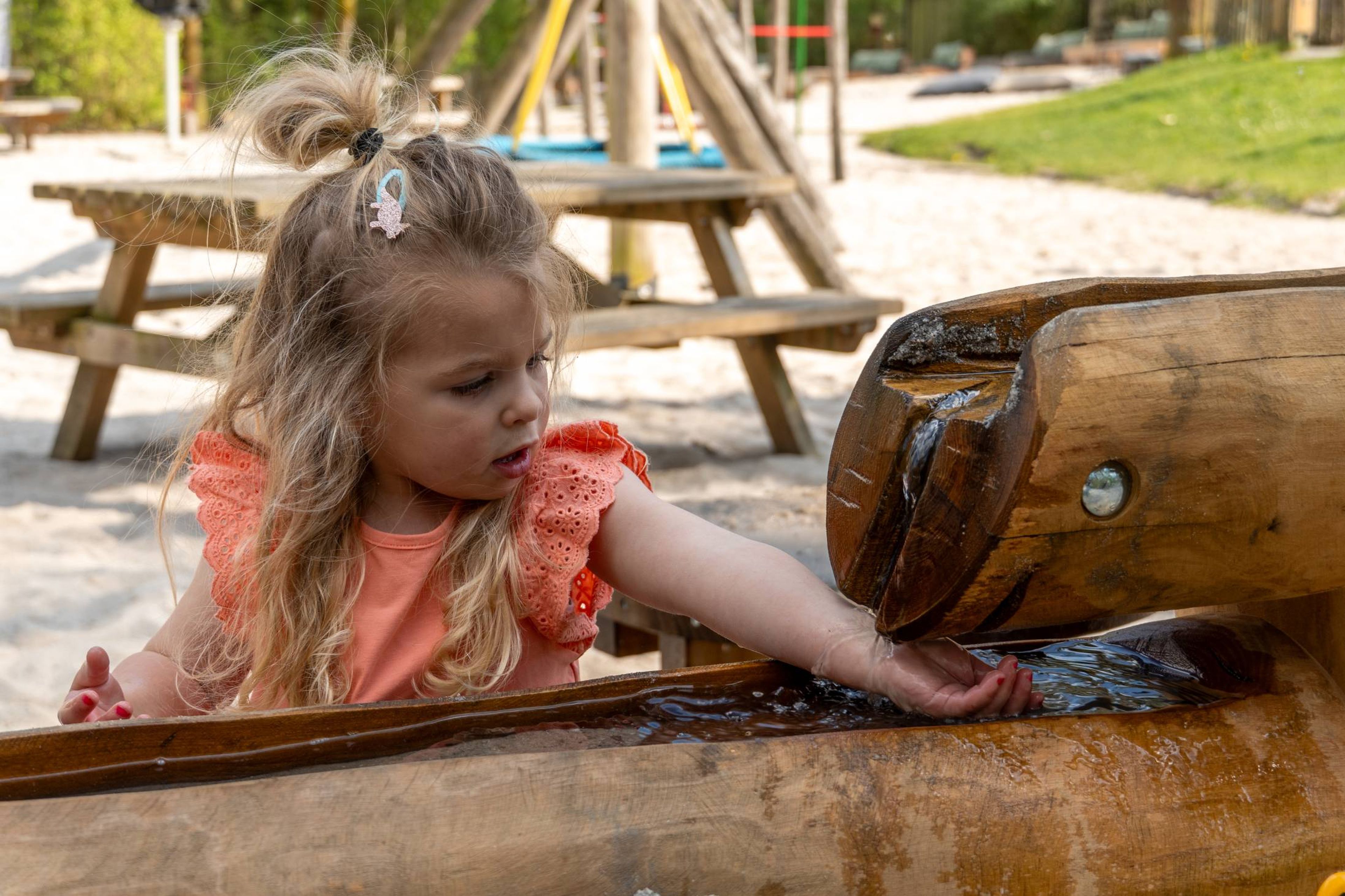 Een meisje speelt met water in de waterspeeltuin bij Klimrijk Brabant