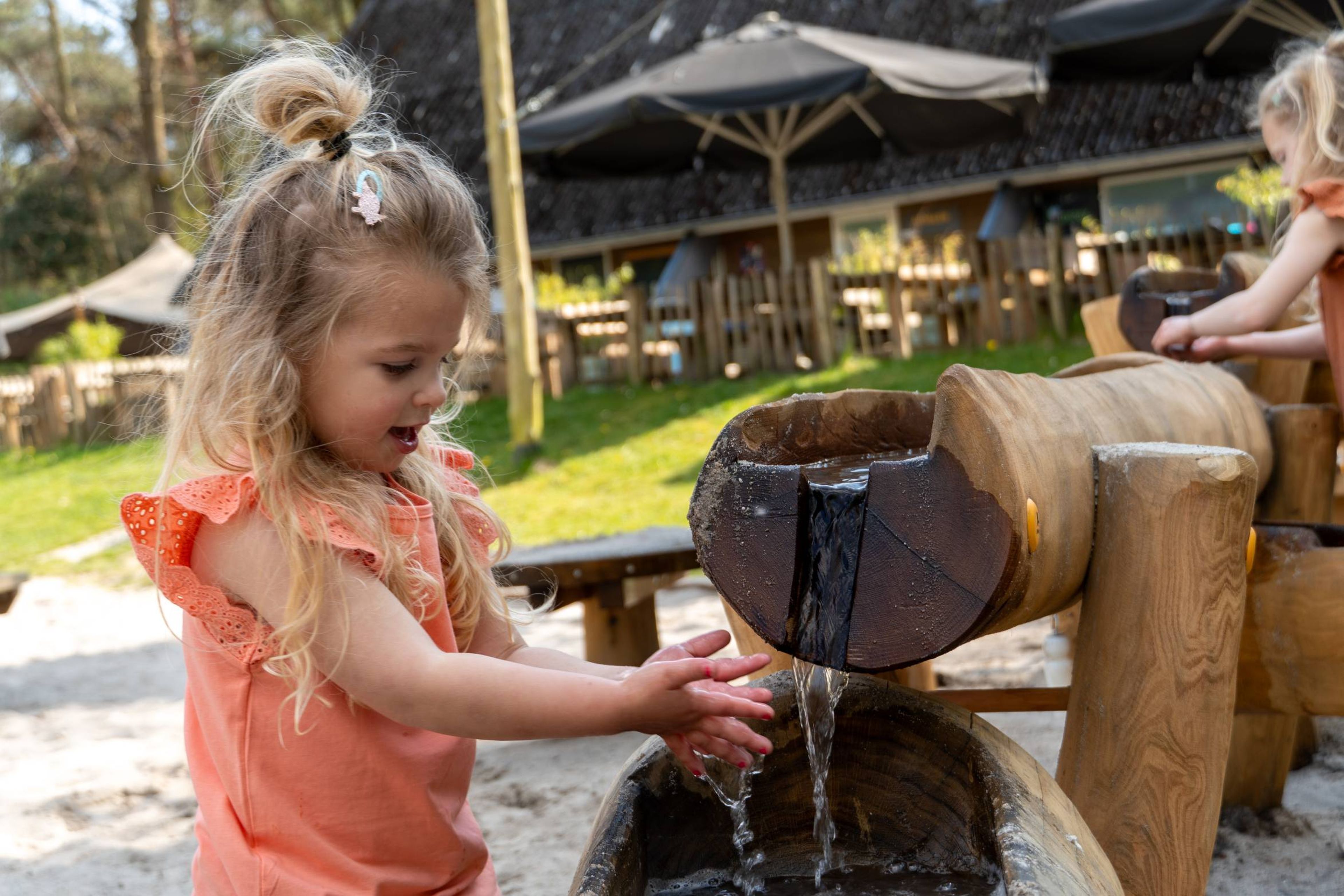 Een meisje speelt met water in de waterspeeltuin bij Klimrijk Brabant