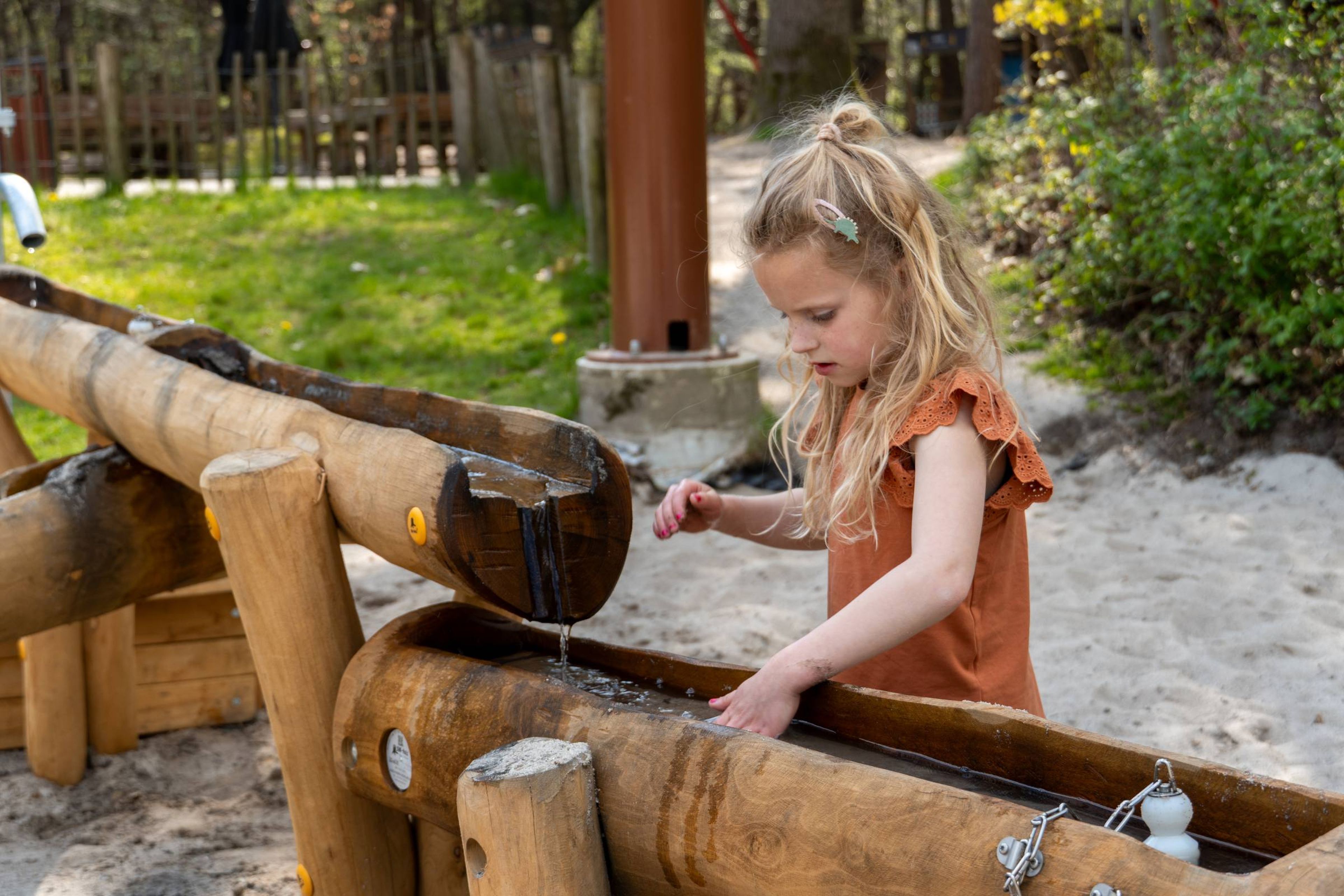 Een meisje speelt met water in de waterspeeltuin bij Klimrijk Brabant