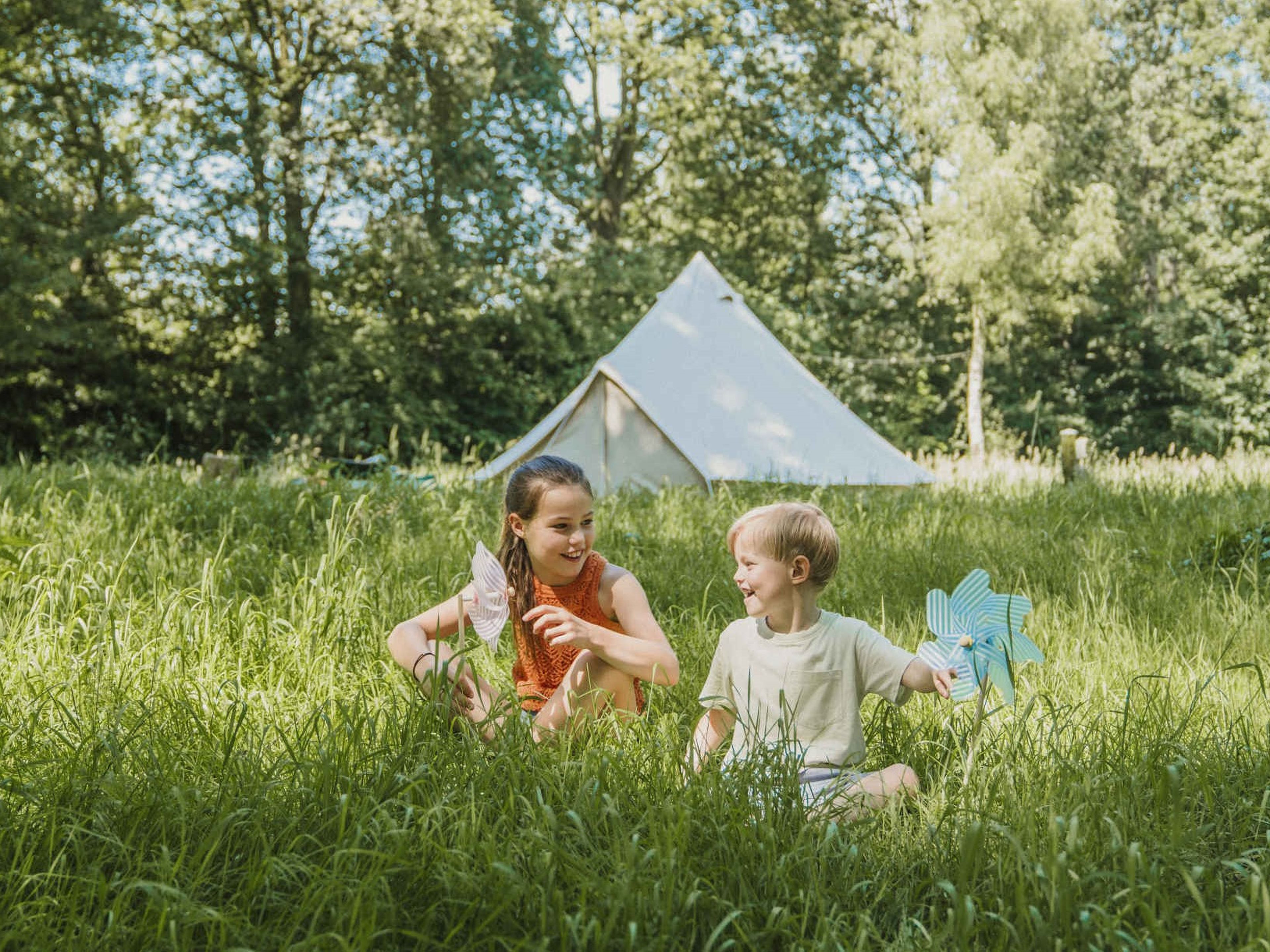 Twee kinderen spelen in het gras bij belevingscamping Vuurvlinder bij Vakantiepark Dierenbos