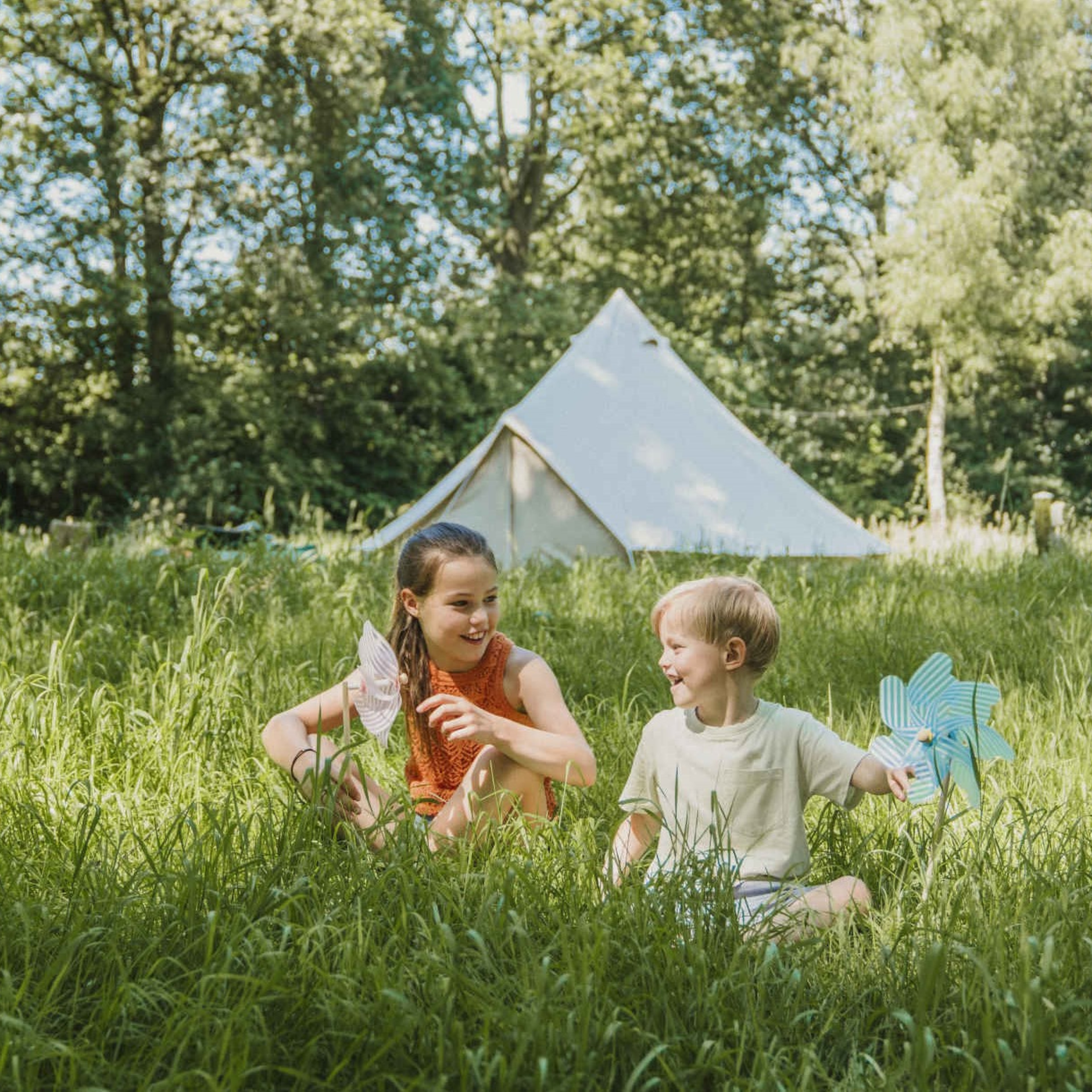 Twee kinderen spelen in het gras bij belevingscamping Vuurvlinder bij Vakantiepark Dierenbos