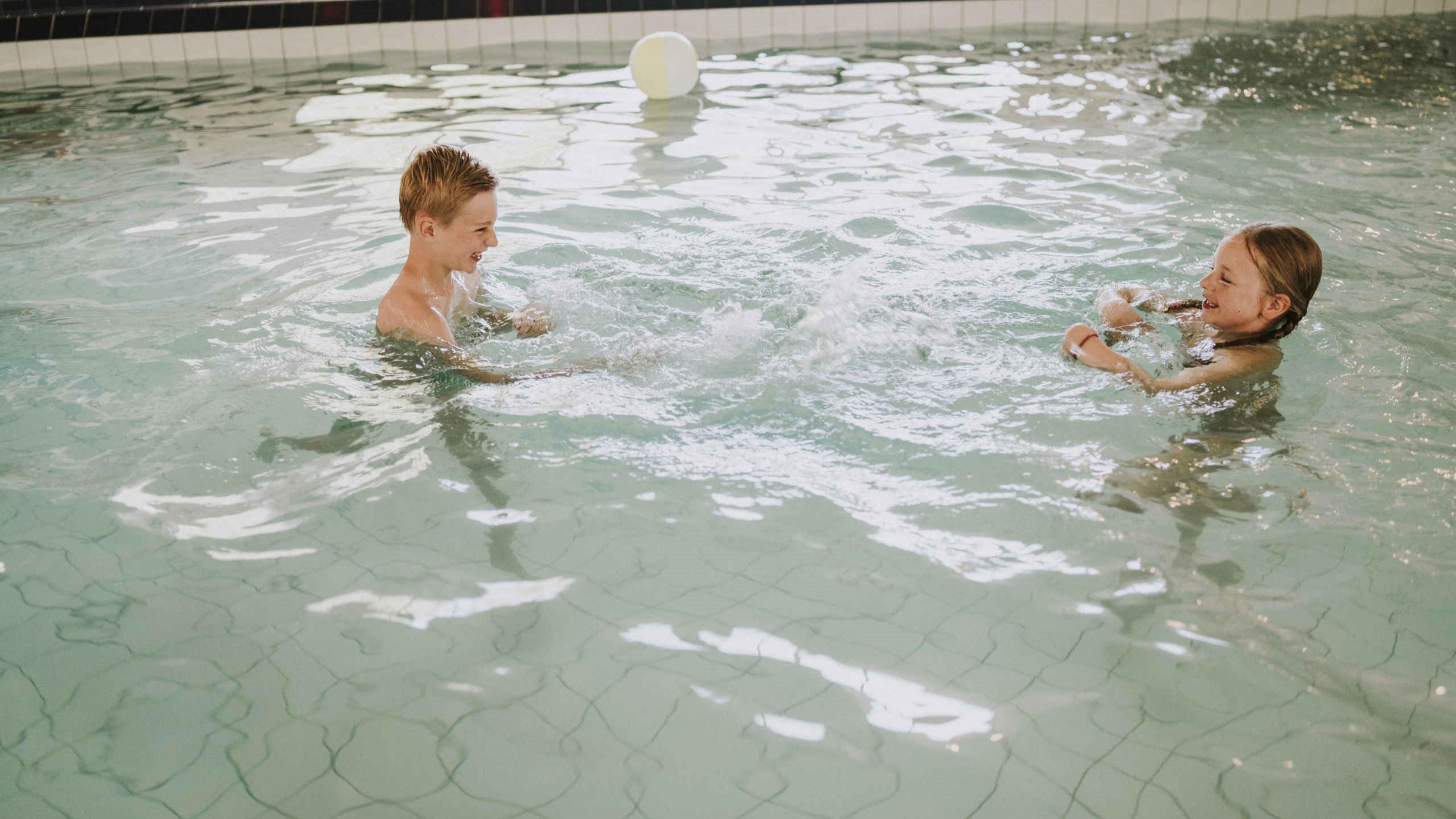 Twee kinderen zwemmen in het buitenbad bij Vakantiepark Dierenbos.