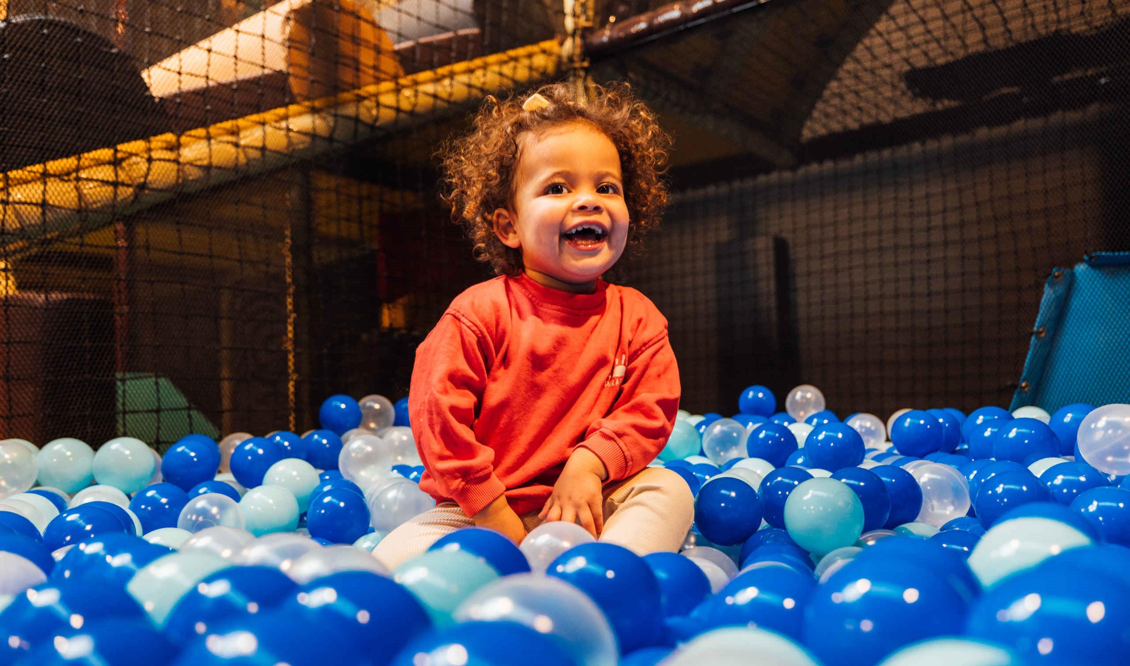 Een kind speelt in de ballenbak bij Speelland Indoor Beekse Bergen, gratis te bezoeken met de Attractiepas van Vakantiepark Dierenbos.