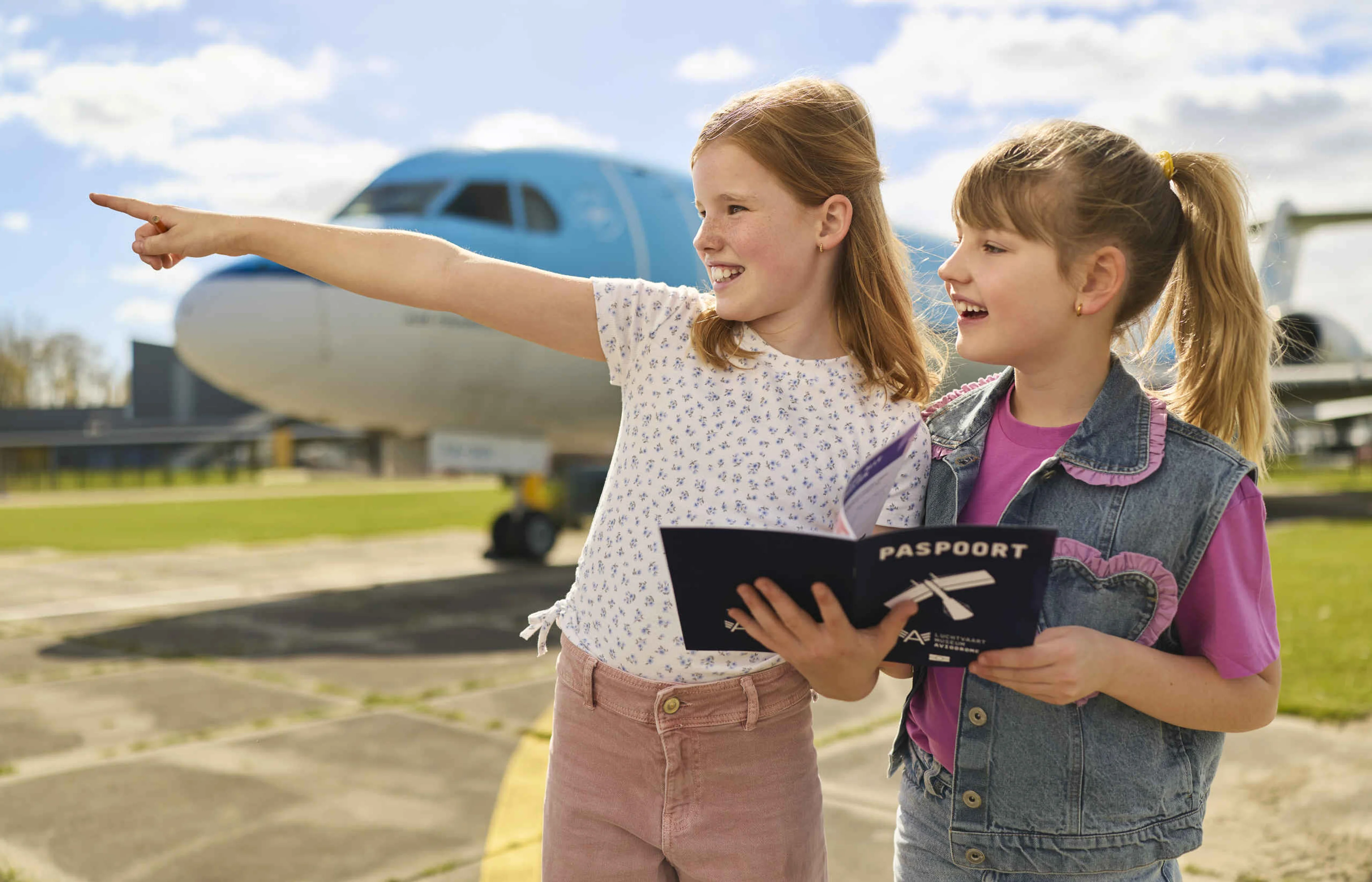 Twee meisjes met hun paspoort op het buitenterrein van Luchtvaartmuseum Aviodrome