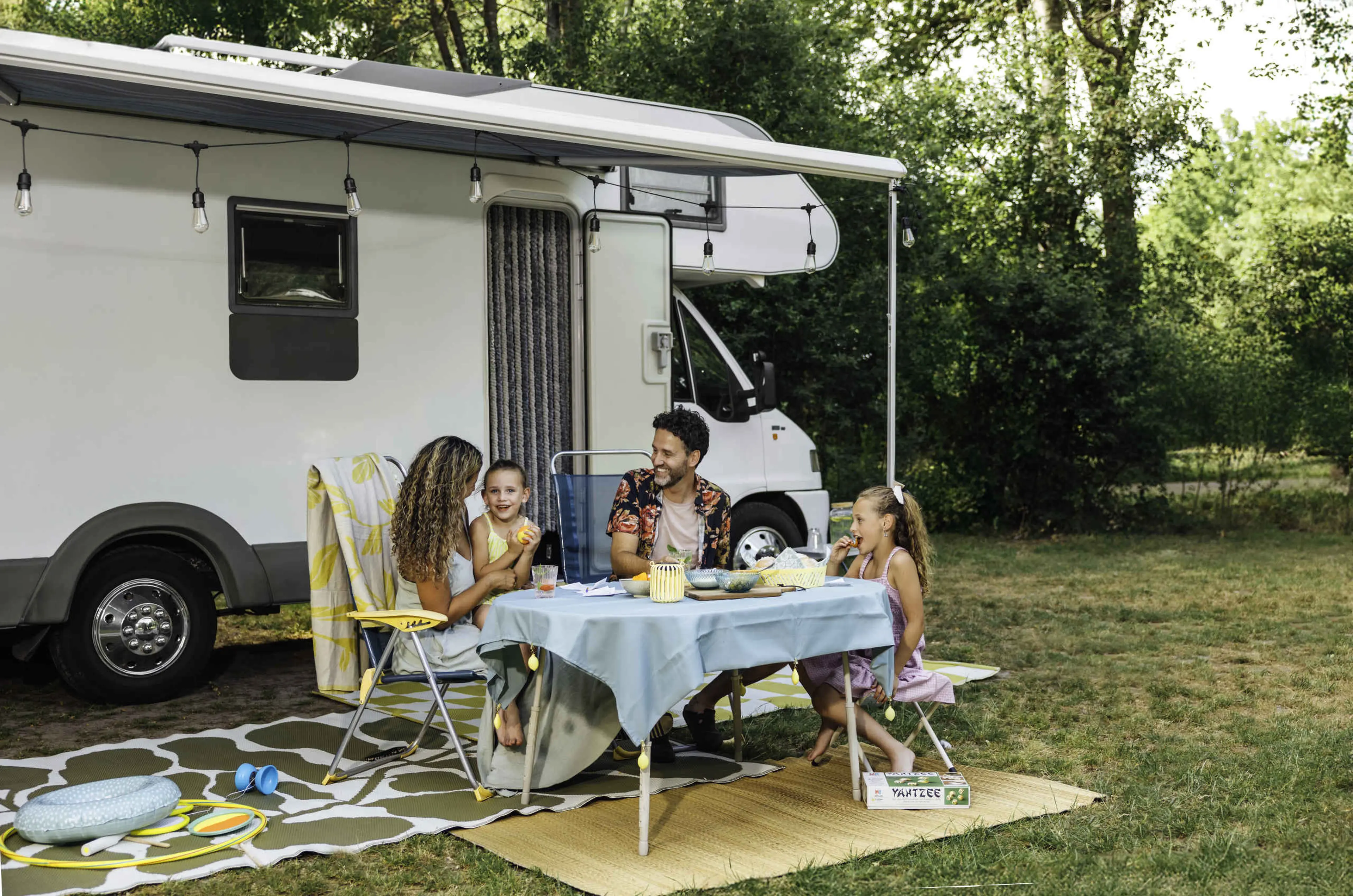 Een man en een vrouw en hun kinderen zitten bij hun camper op de camping bij Lake Resort Beekse Bergen.