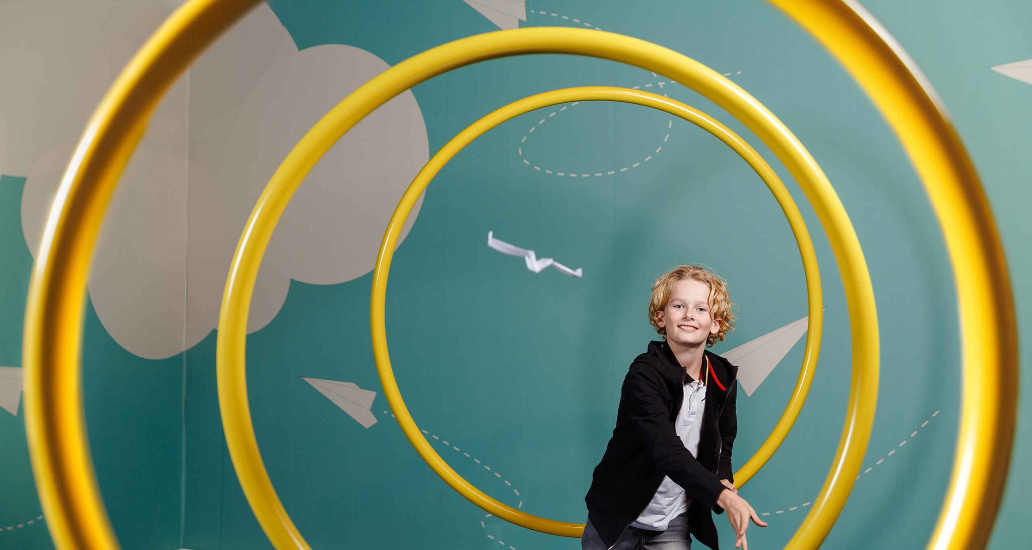 Een kind gooit een papieren vliegtuigje in Luchtvaartmuseum Aviodrome