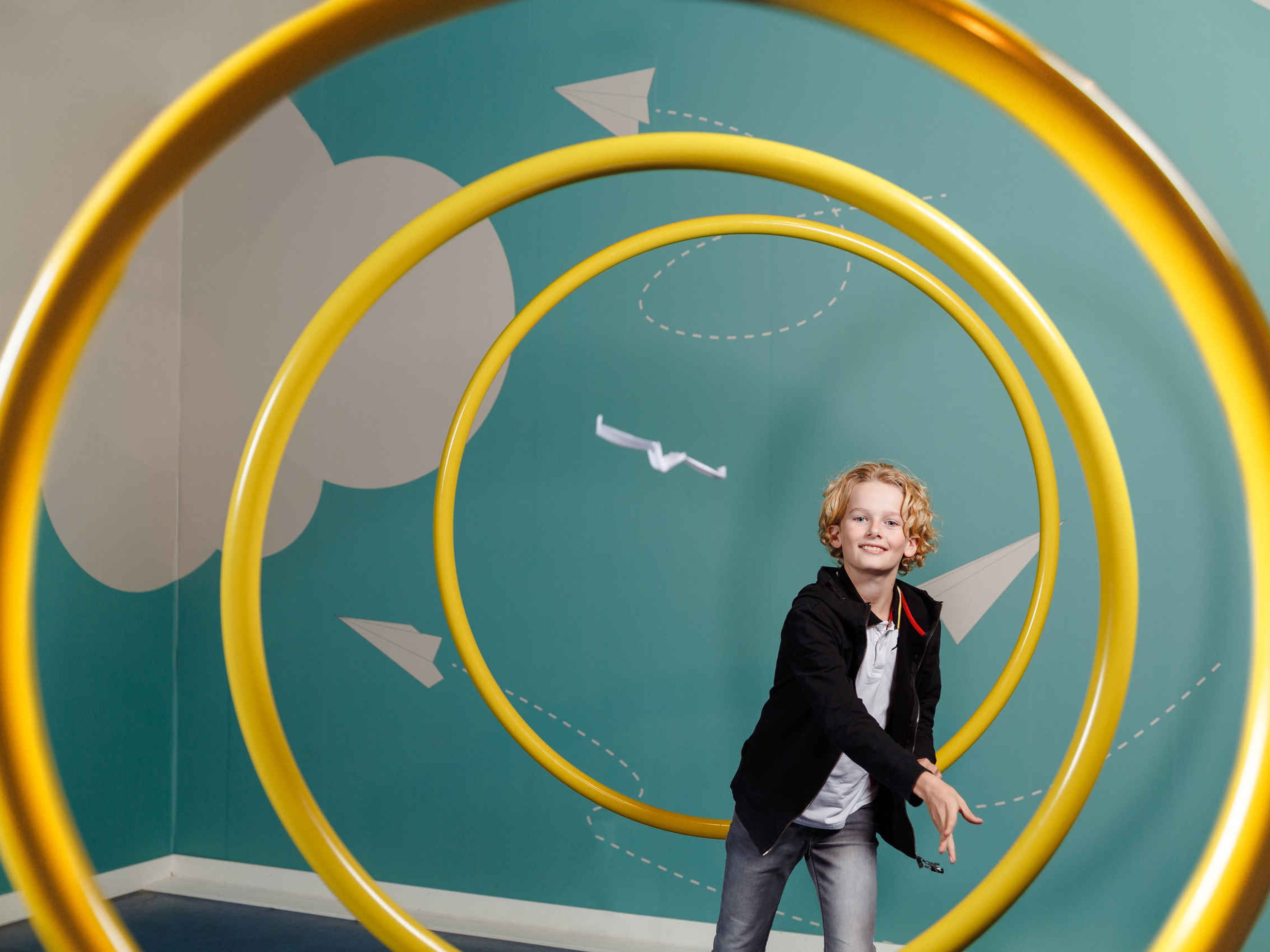 Een kind gooit een papieren vliegtuigje in Luchtvaartmuseum Aviodrome