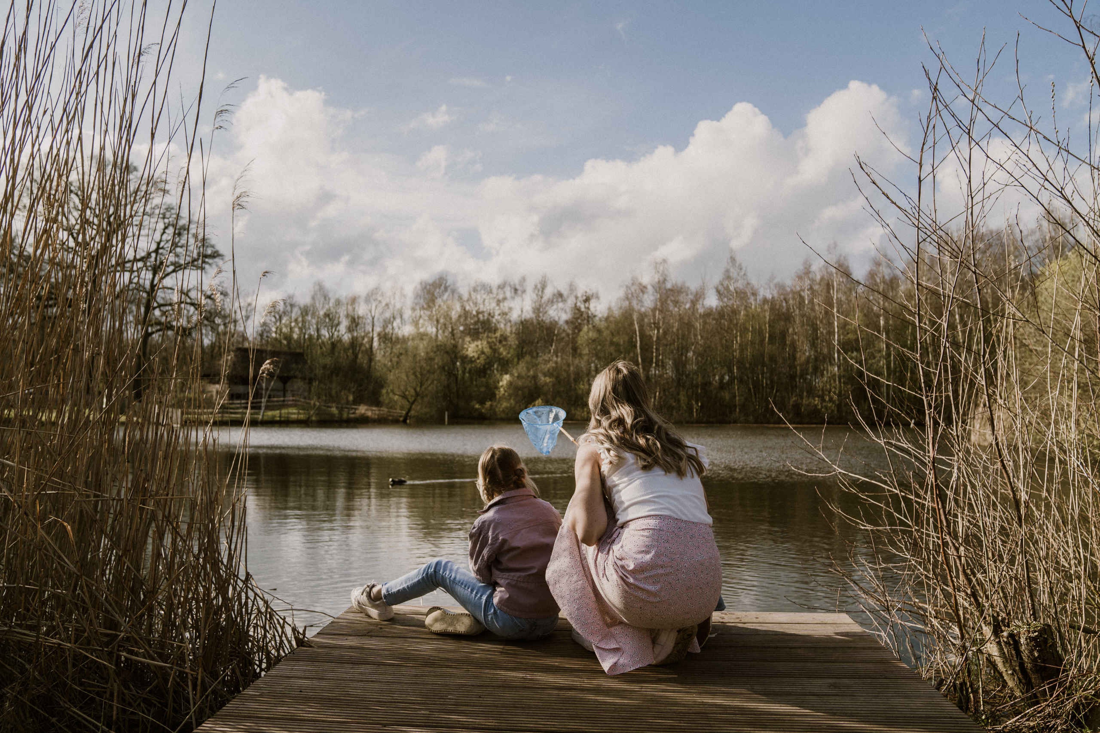 Moeder en kind tussen het riet op de steiger van de visvijver van Vakantiepark Dierenbos