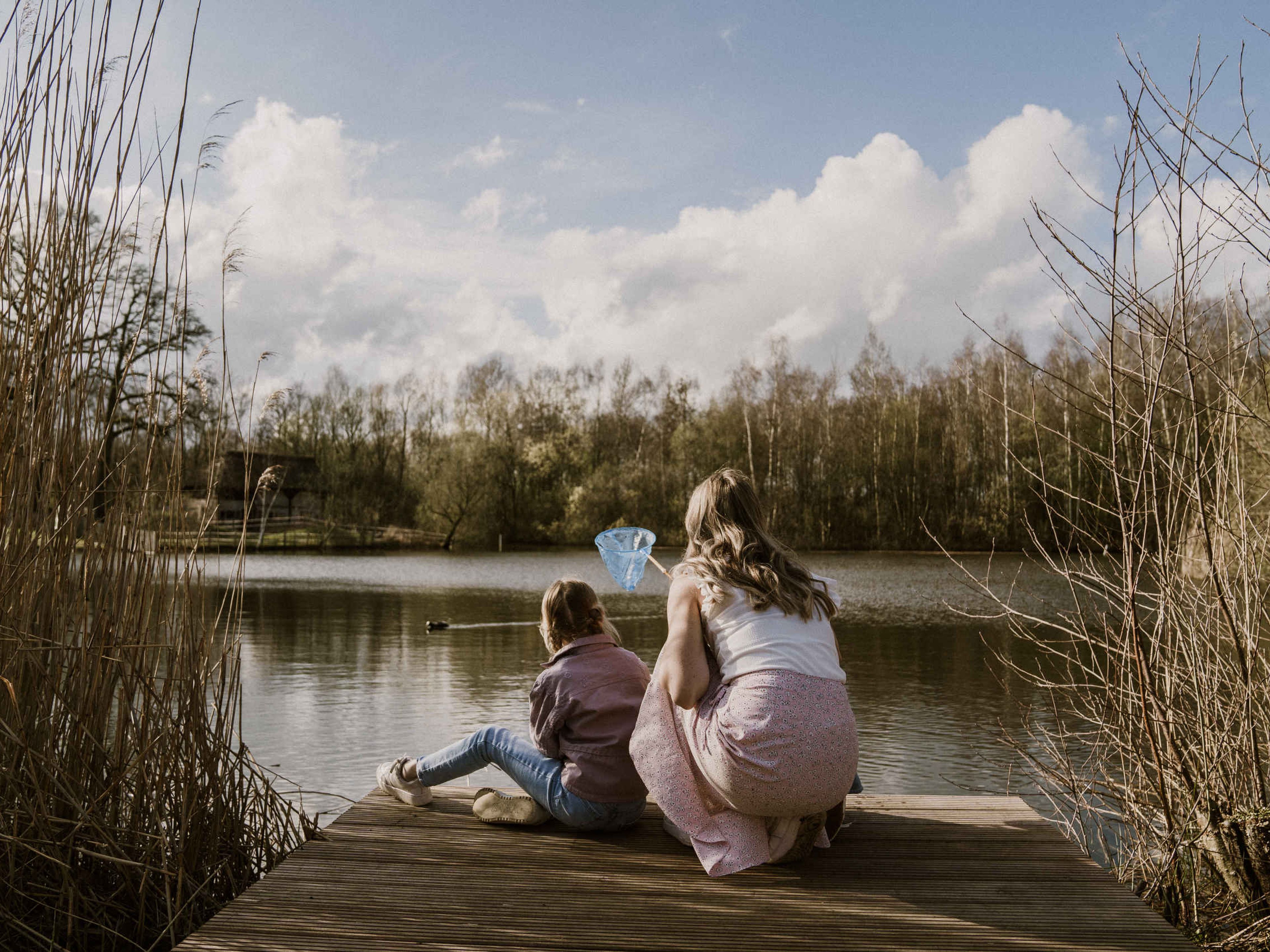 Moeder en kind tussen het riet op de steiger van de visvijver van Vakantiepark Dierenbos