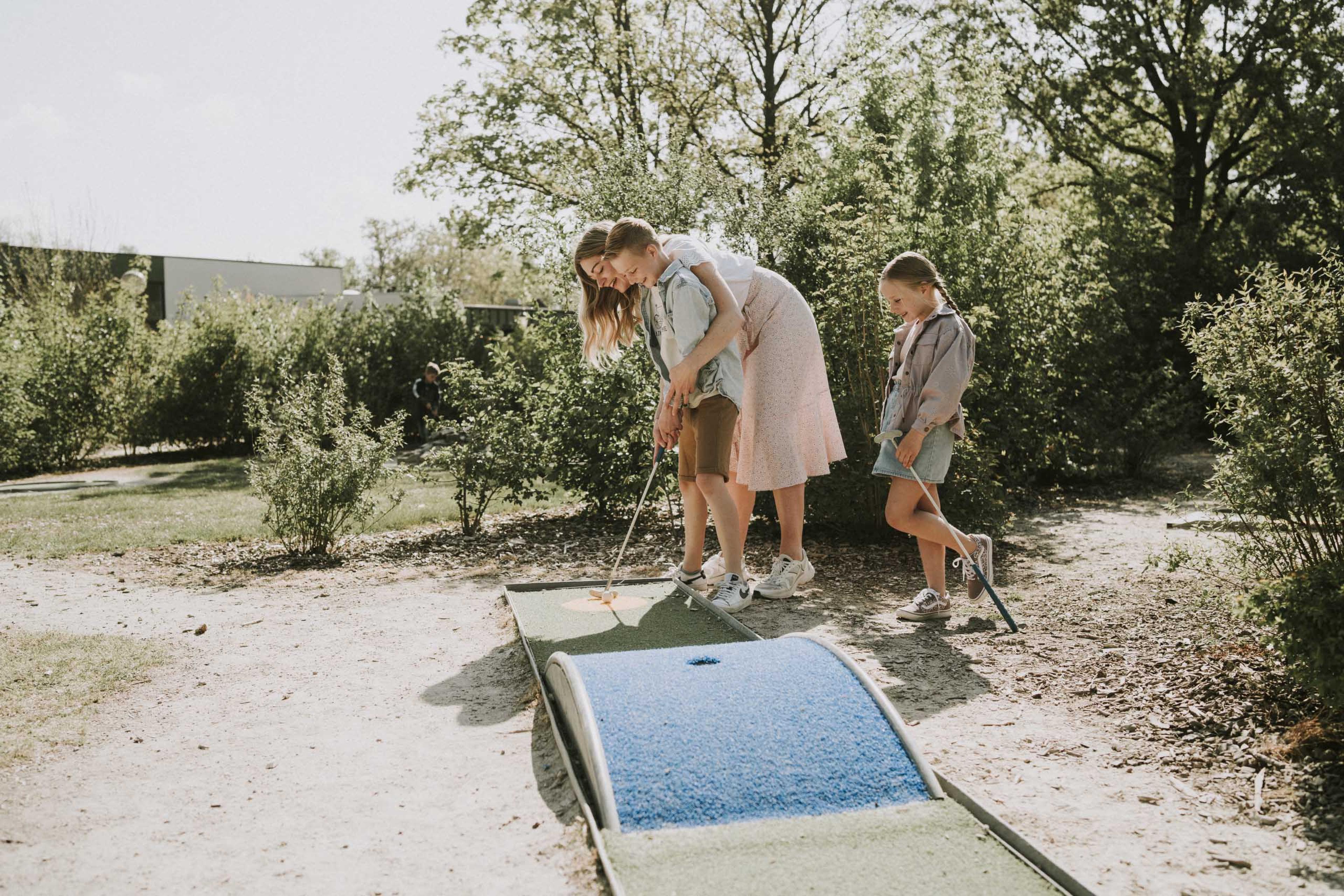 Moeder en zoon spelen samen midgetgolf op de midgetgolfbaan van Vakantiepark Dierenbos