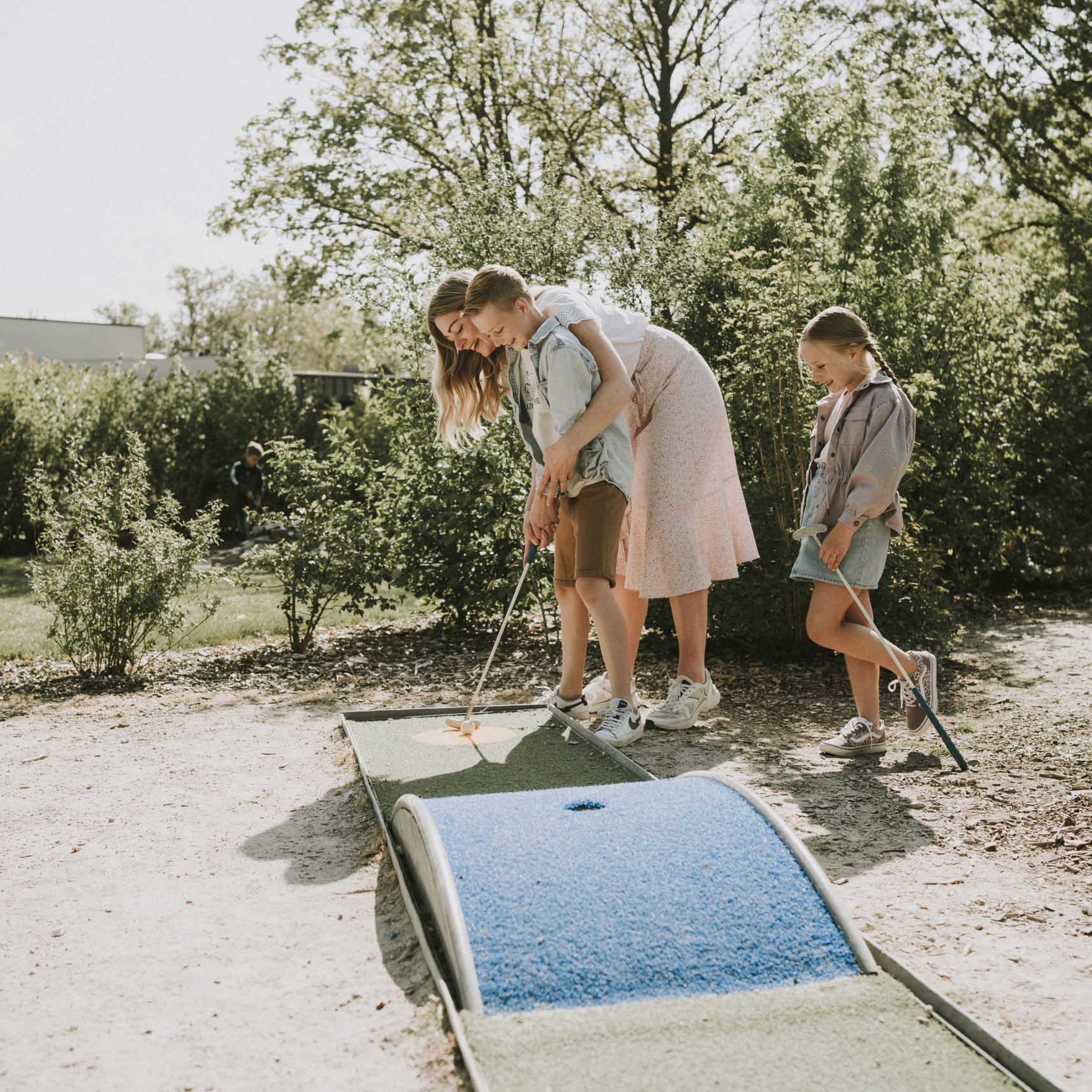Moeder en zoon spelen samen midgetgolf op de midgetgolfbaan van Vakantiepark Dierenbos