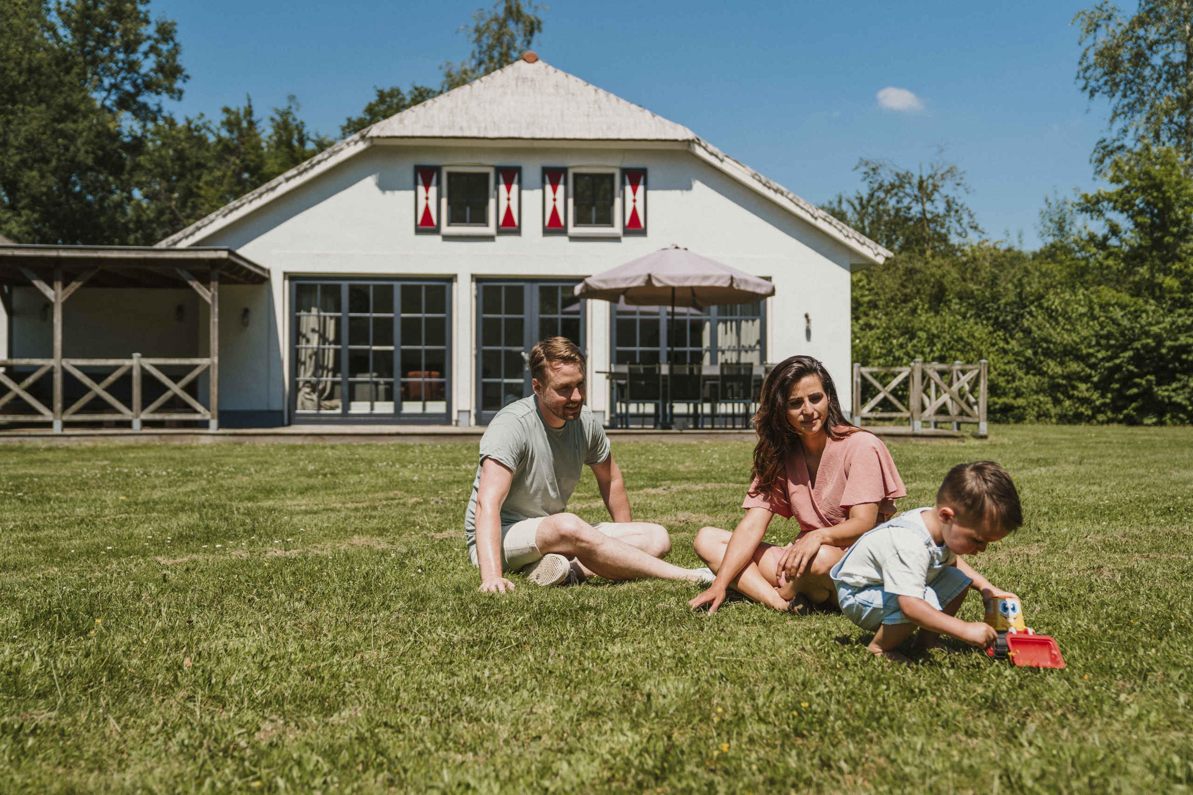 Een gezin speelt in het grasveld voor Villa Alpaca bij Vakantiepark Dierenbos