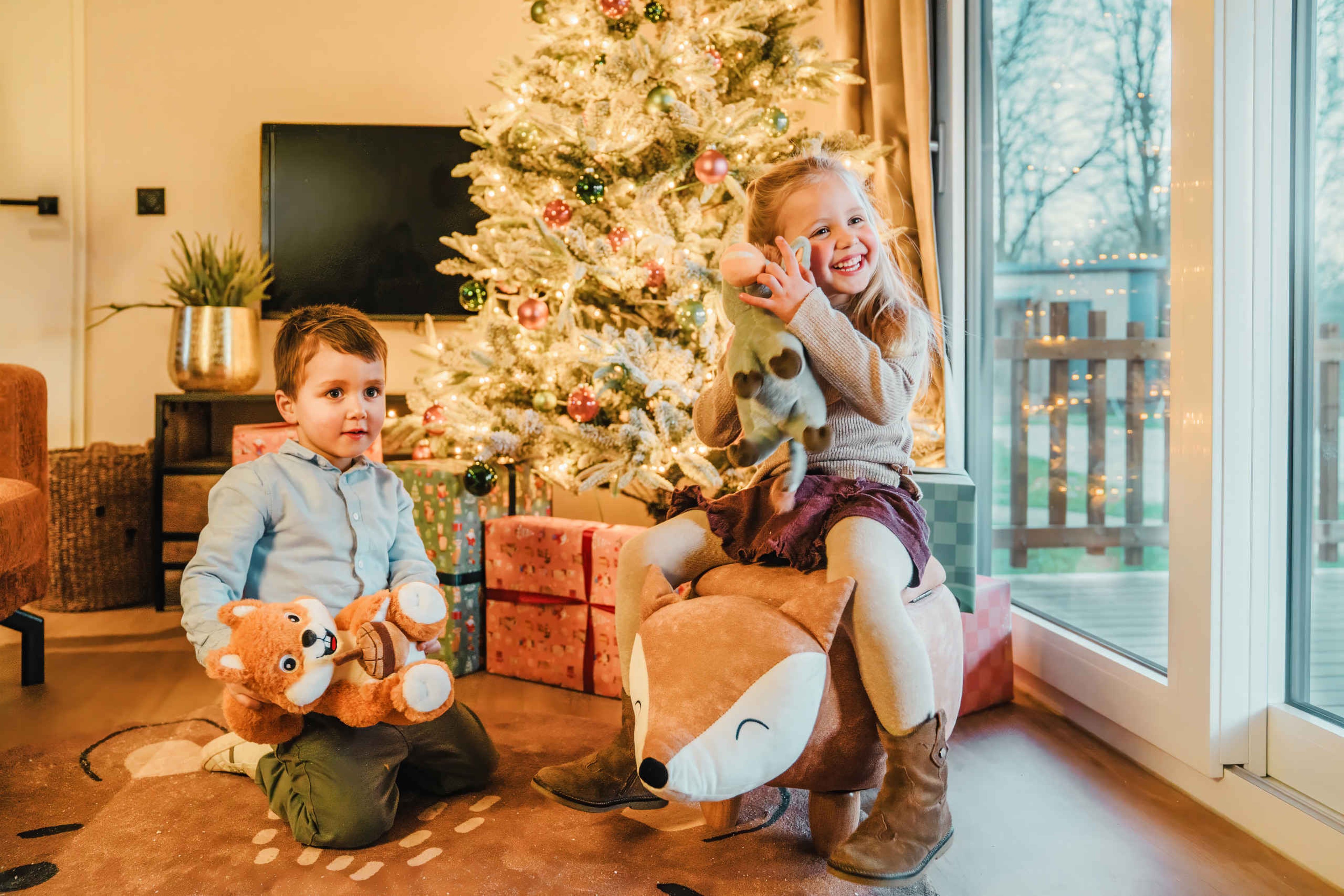 Kinderen bij de kerstboom met cadeau's in Cottage Edelhert op Vakantiepark Dierenbos