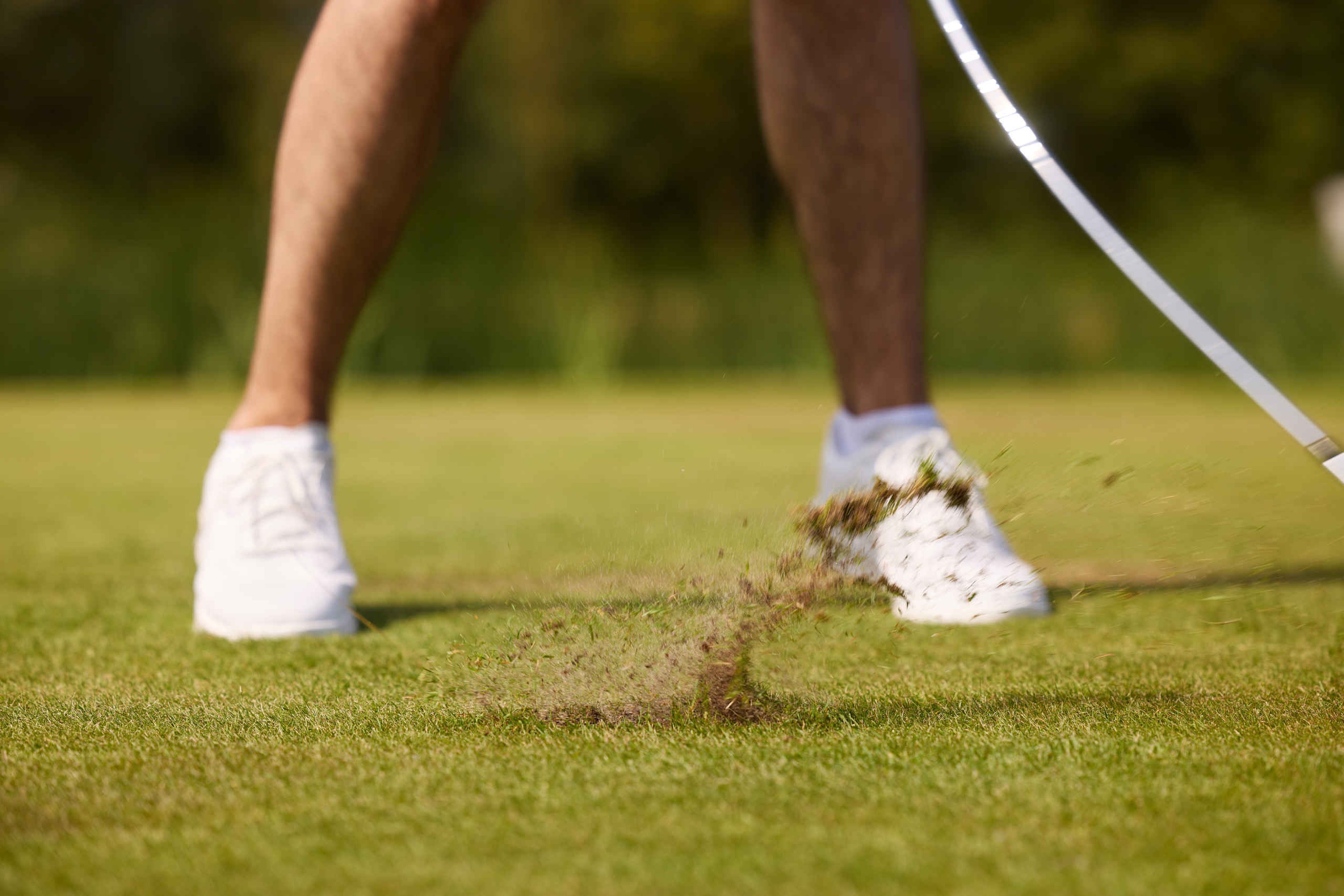 Een man maakt een divot na het maken van een golfslag op de libellebaan van Golf De Gulbergen