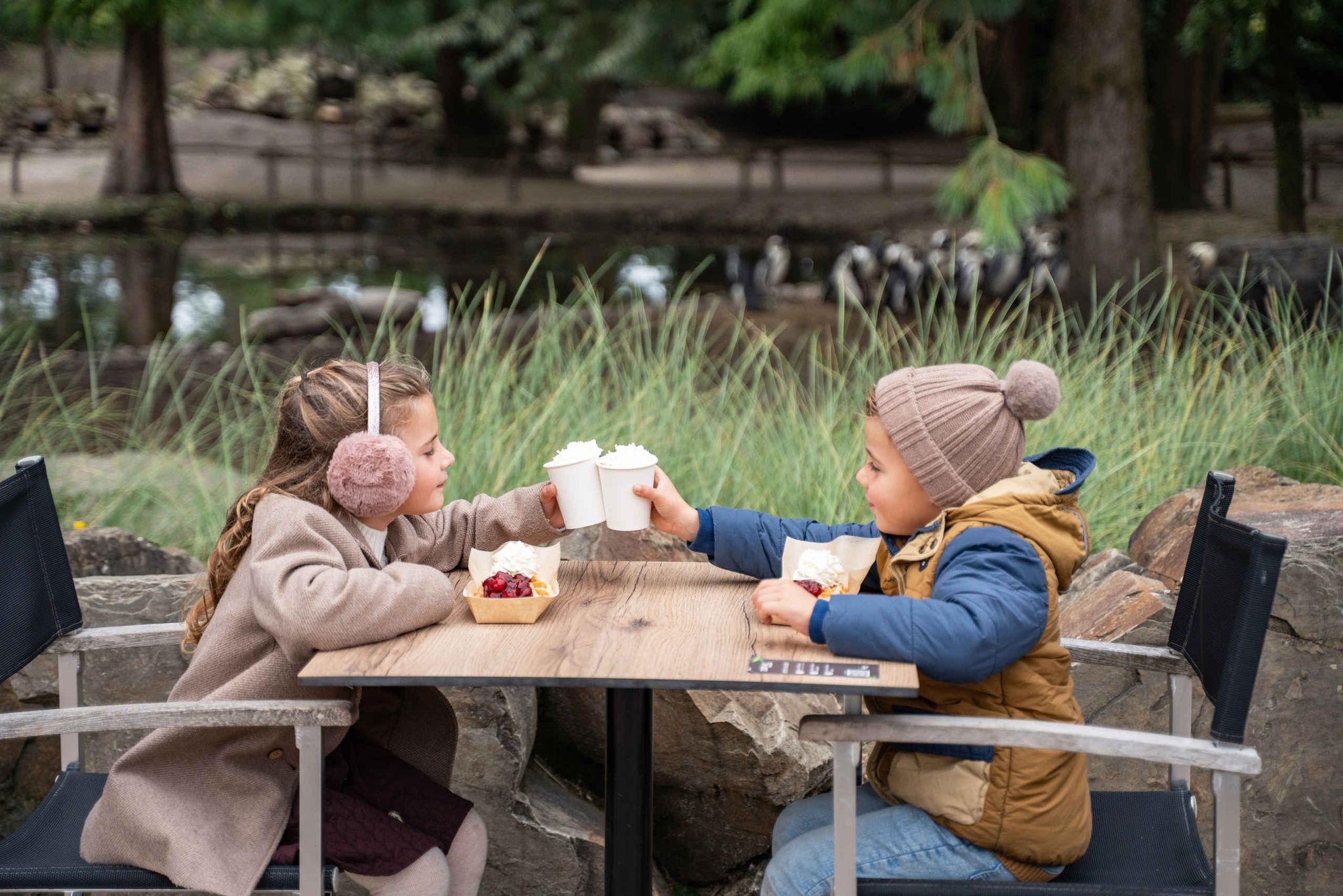Twee kinderen zitten op het terras en genieten van een warme drank en de horecadeal tijdens IJstijd in ZooParc Overloon