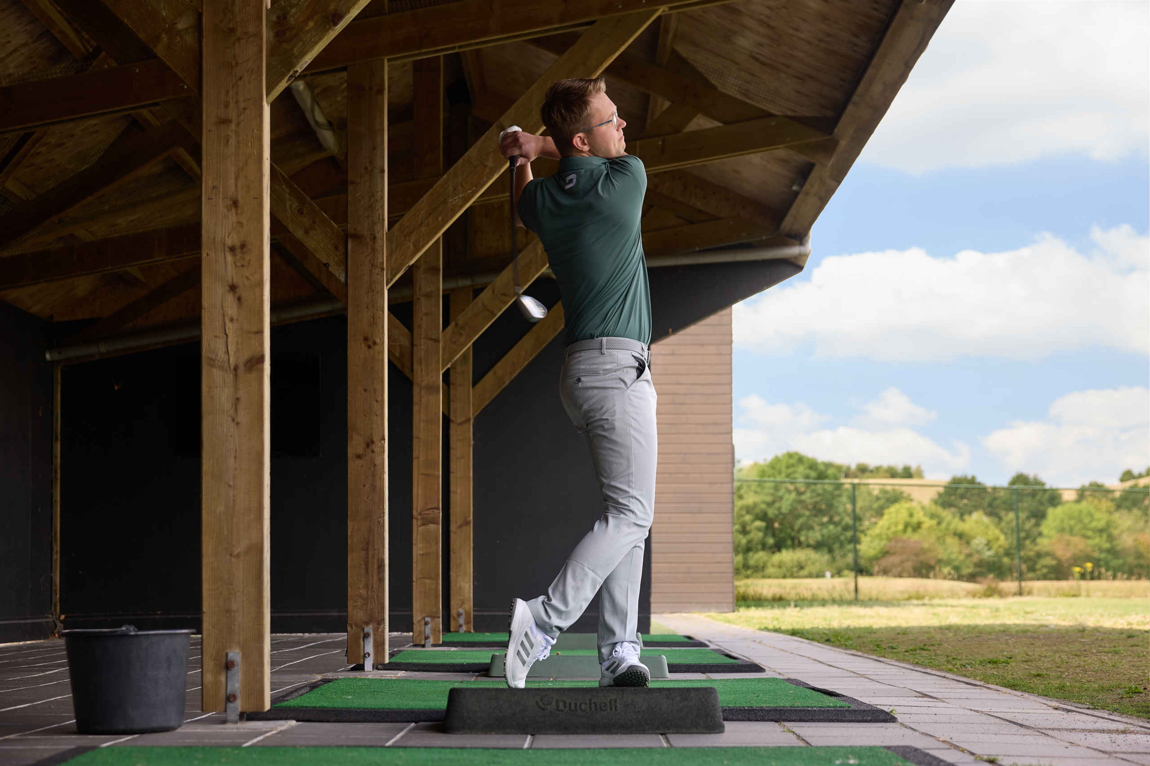 Een golfer slaat een golfbal op de driving range van Golf De Gulbergen
