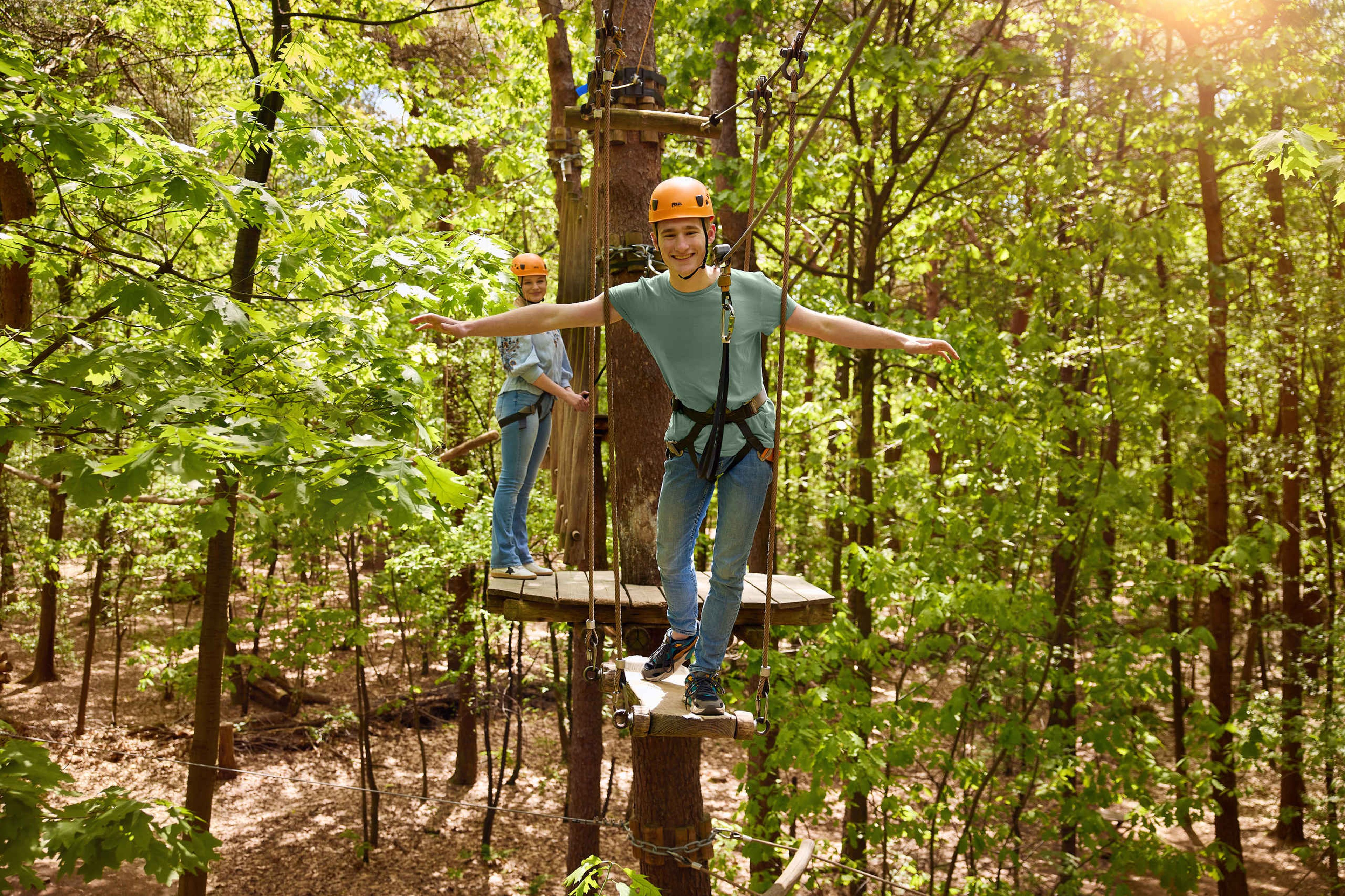 Een jongen en een meisje klimmen op het klimparcours bij Klimrijk Brabant.