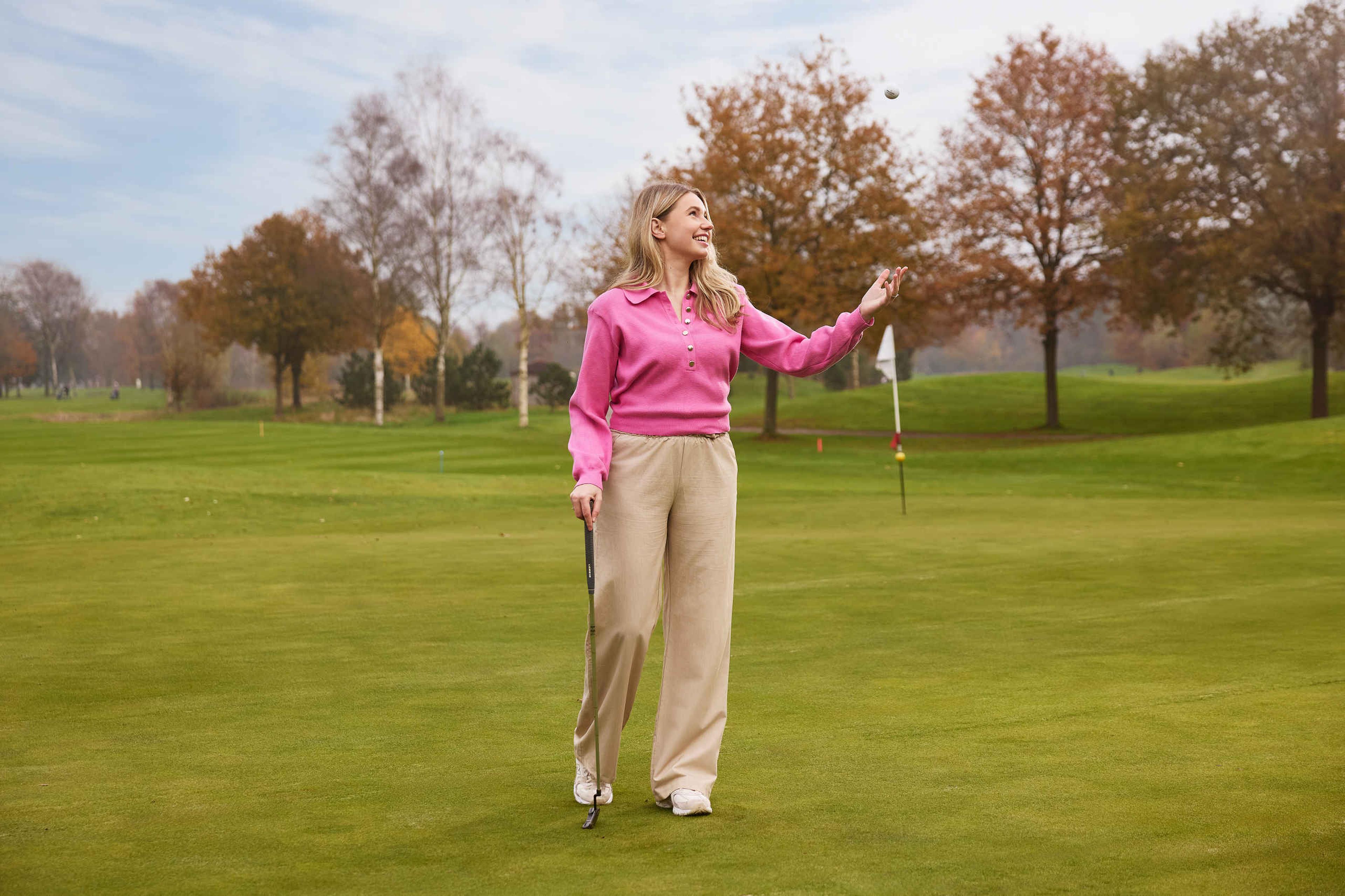 Een dame gooit een golfbal op de green met een putter in de hand bij Golf De Gulbergen