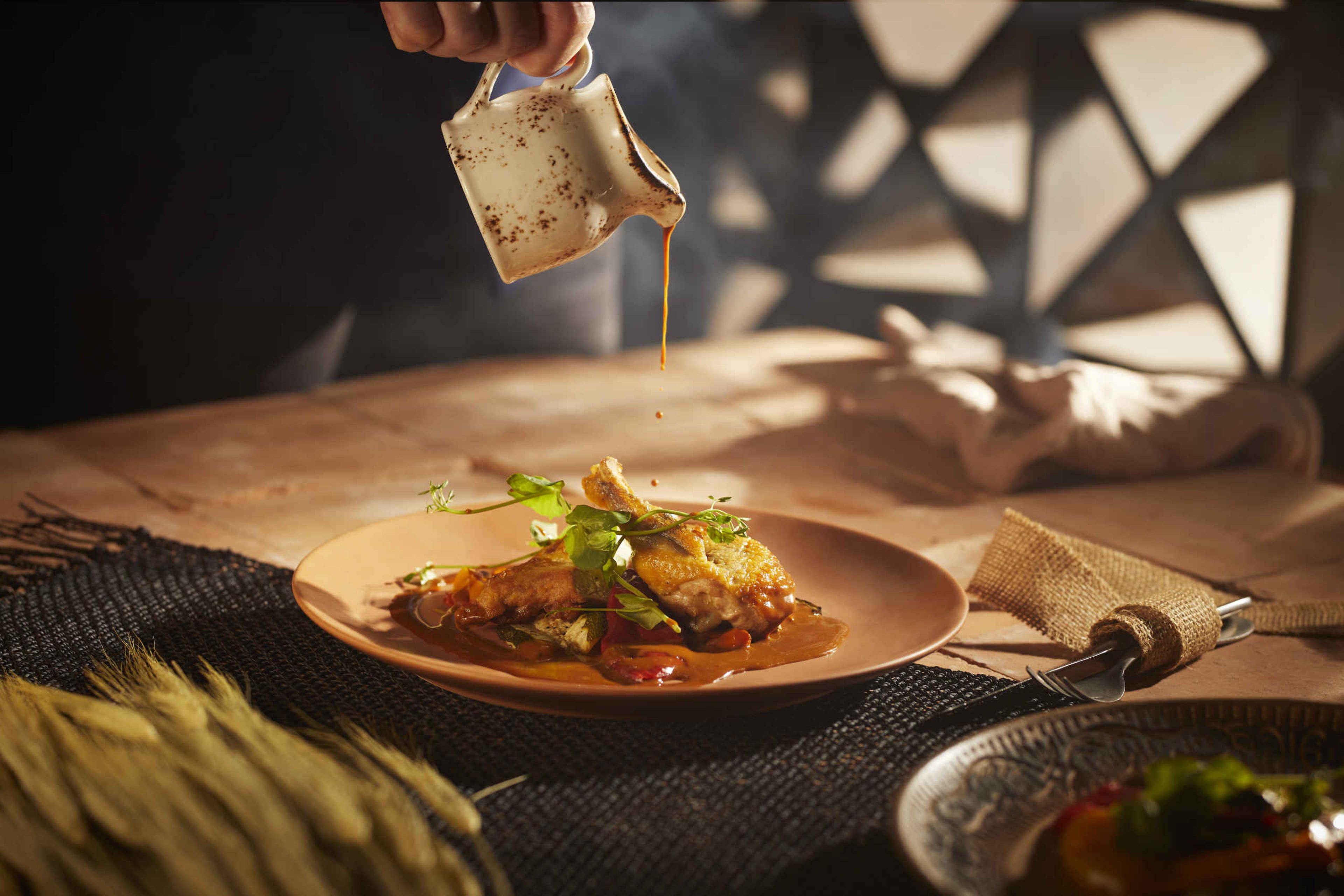 De chefkok giet de saus voorzichtig over een gerecht met parelhoen bij restaurant Moto in Safari Resort Beekse Bergen.