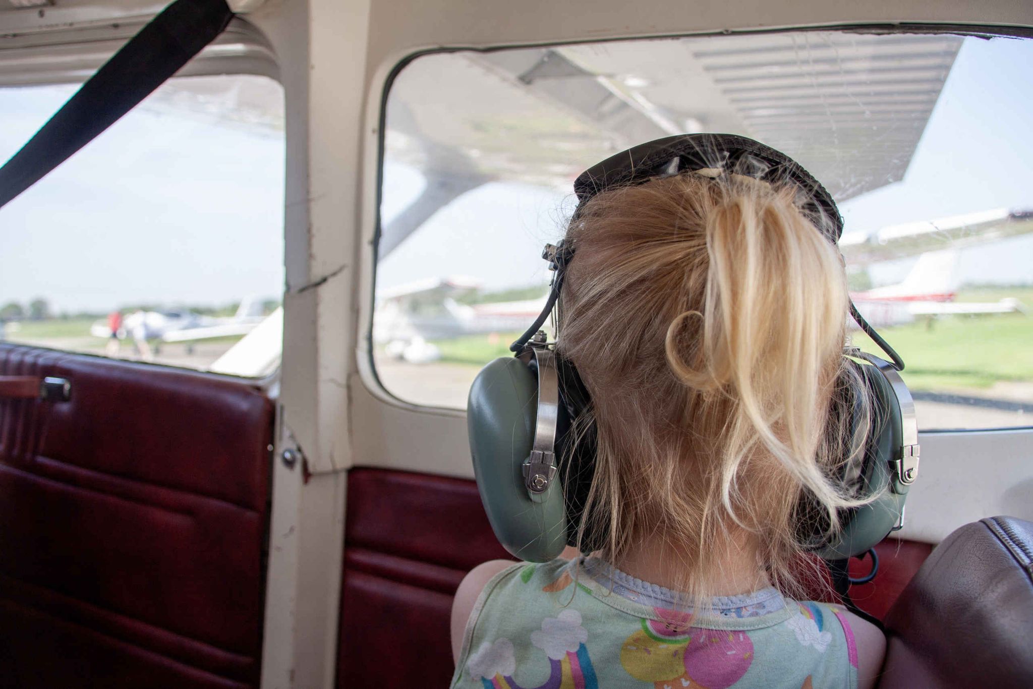 Een meisje met headset zit in een vliegtuig klaar voor een rondvlucht bij Luchtvaartmuseum Aviodrome
