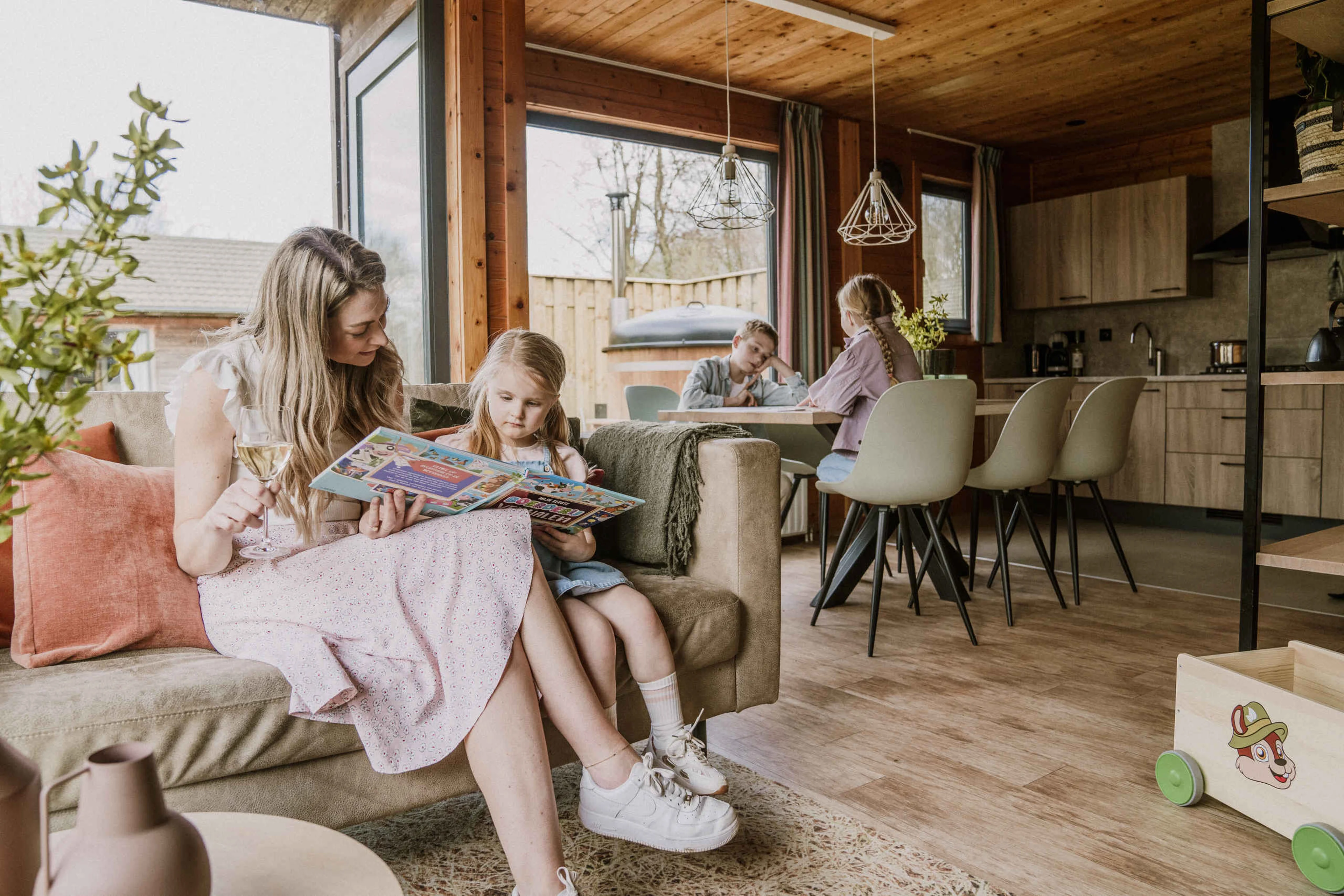 Gezin in de woonkamer van de Kidsbungalow Damhert op Vakantiepark Dierenbos