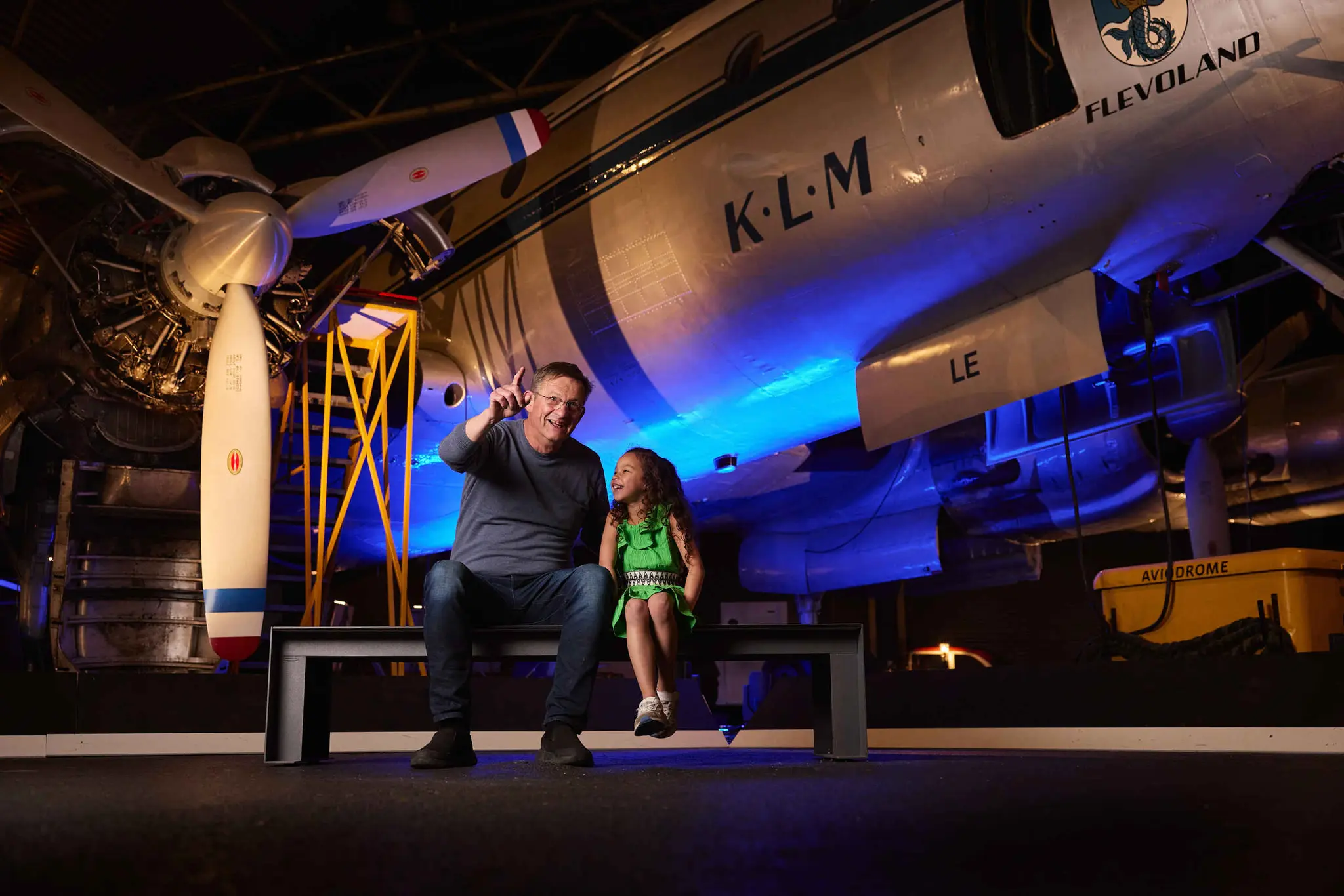 Een opa en kleindochter zitten op een bankje in de binnenexpositie van Luchtvaartmuseum Aviodrome