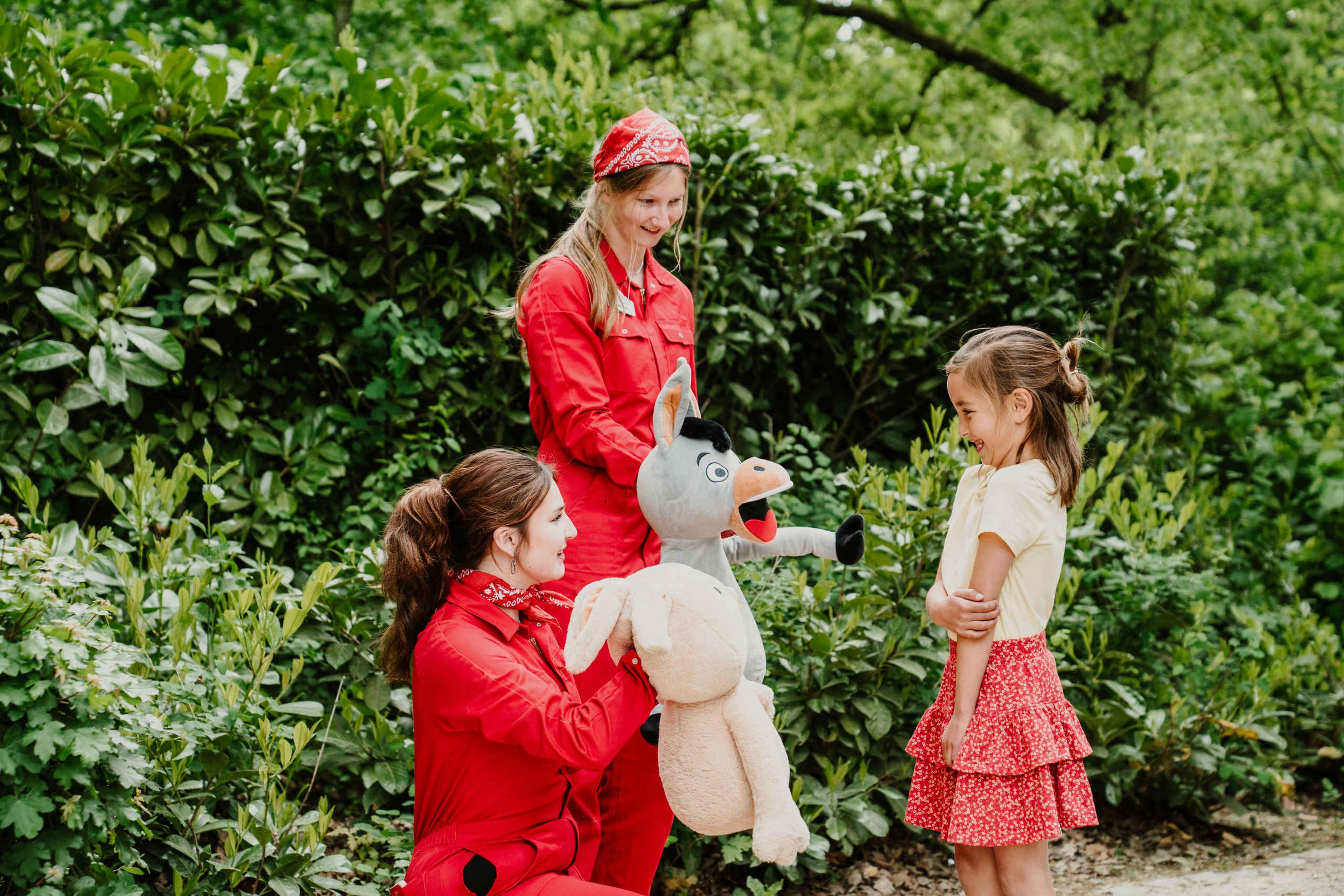Twee animatieleden met handpoppen staan bij een meisje op Vakantiepark Dierenbos.
