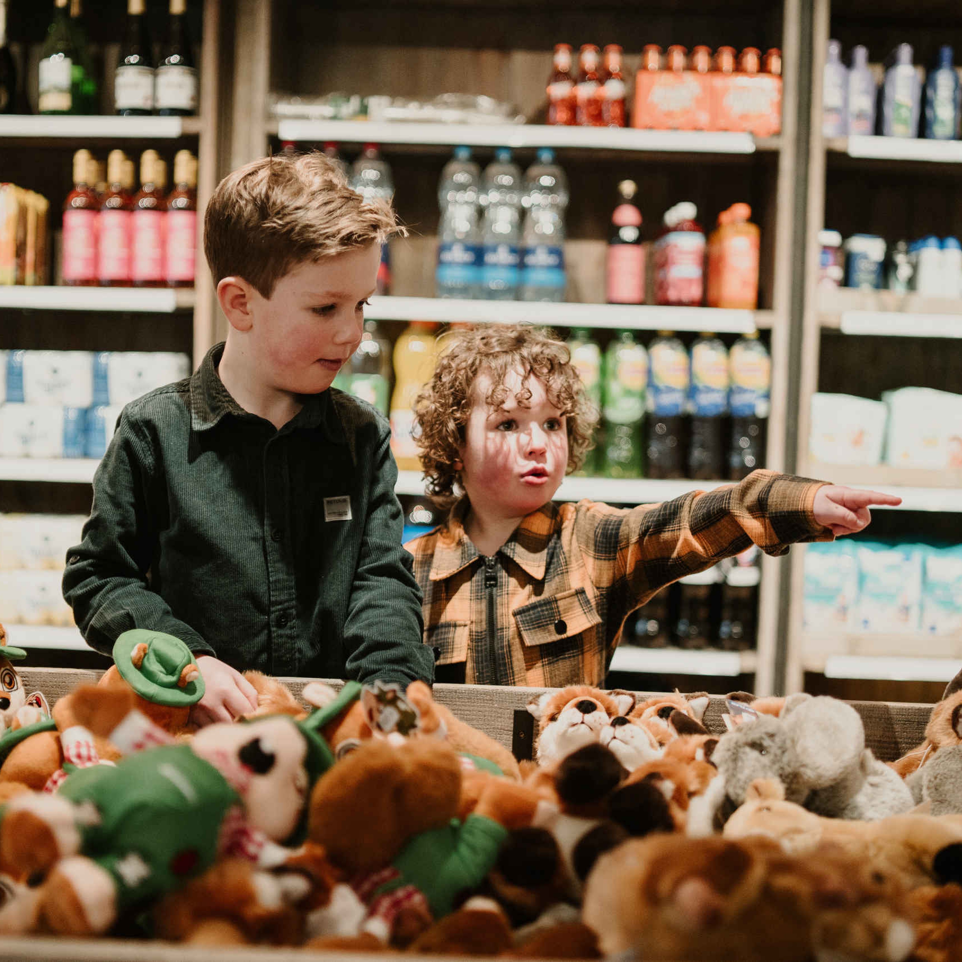 Twee kinderen kijken bij de knuffels bij mini-market Broodnodig bij Vakantiepark Dierenbos.