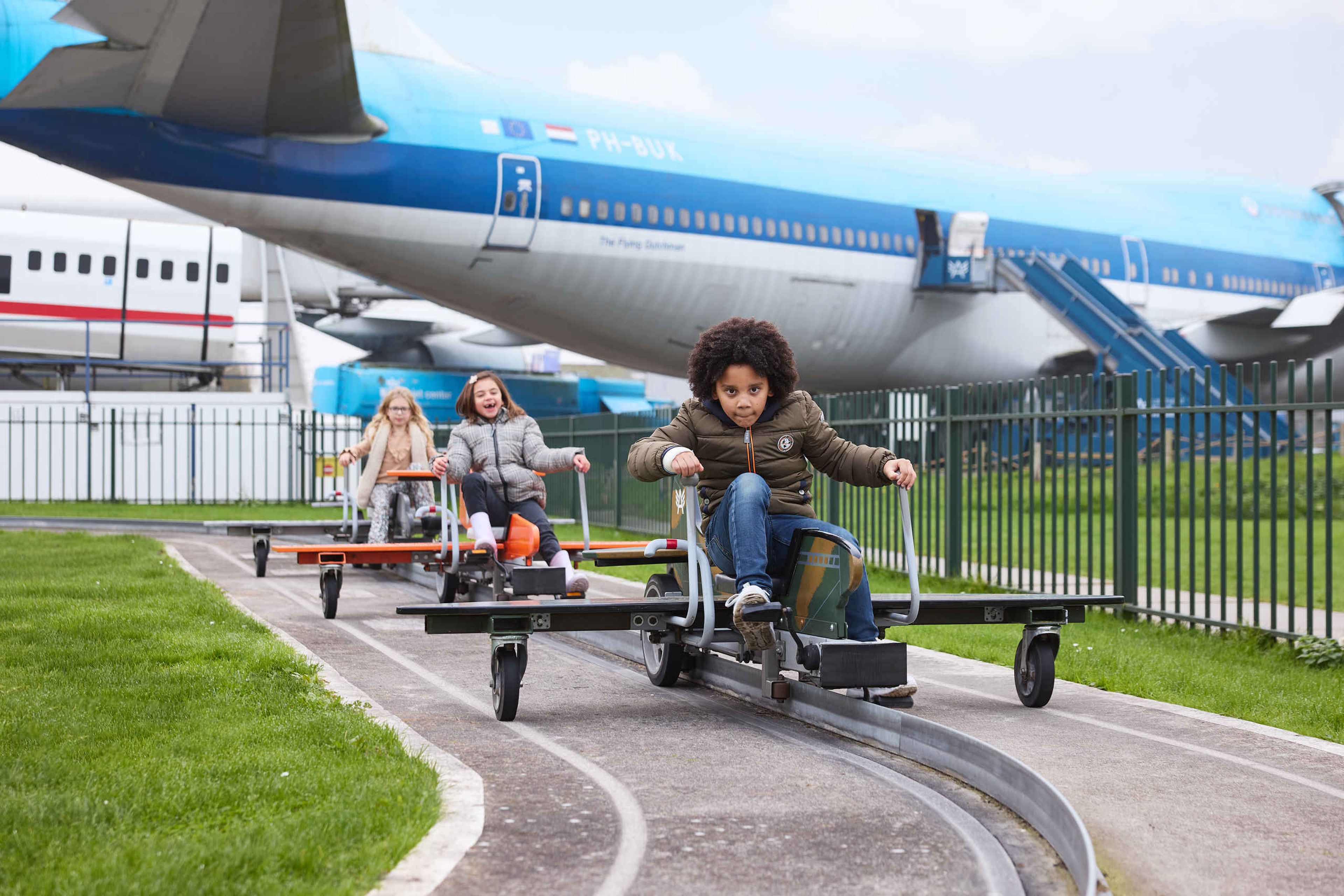 Drie kinderen op de Aviodrome Airport fietsbaan buiten bij Luchtvaartmuseum Aviodrome