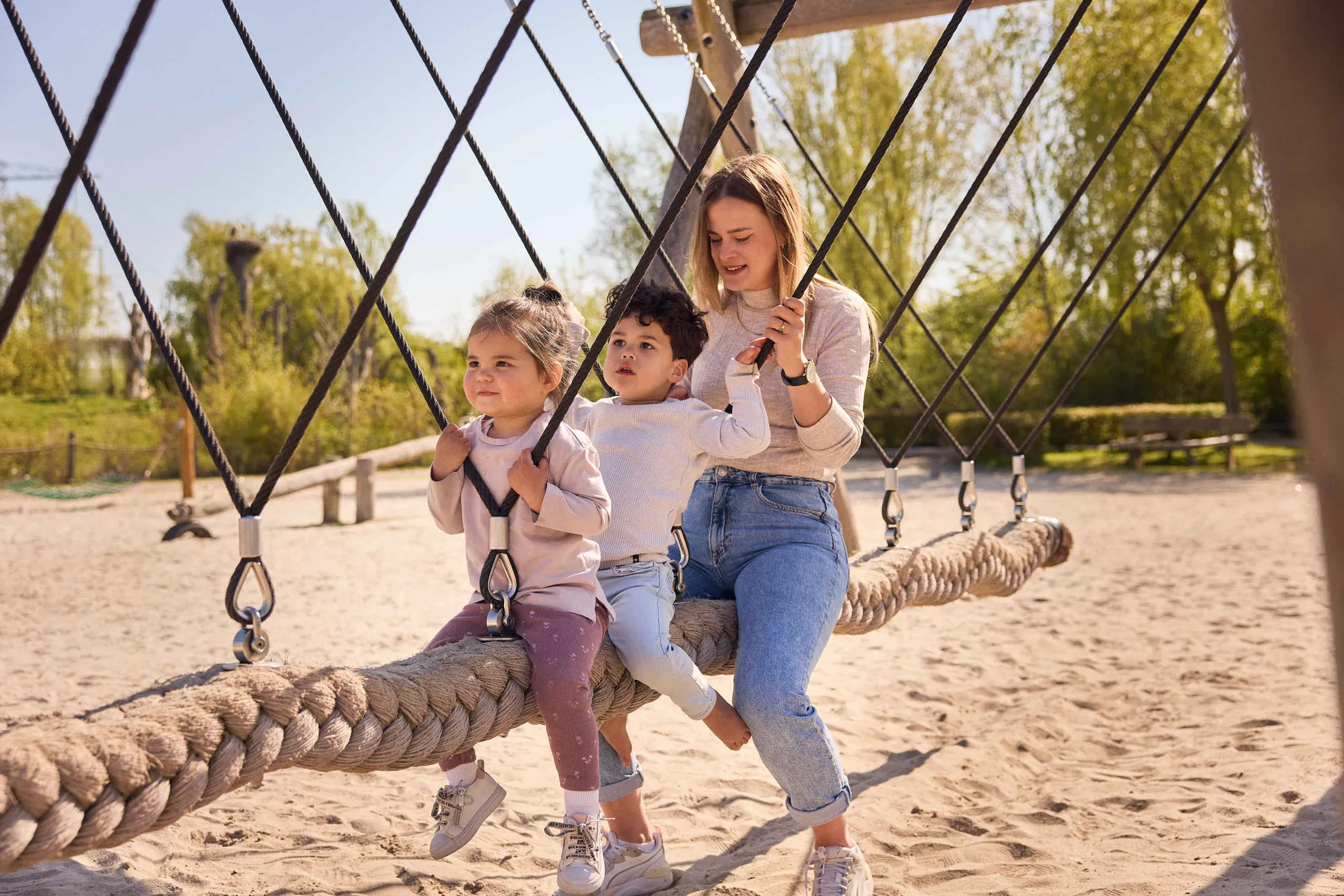 Een vrouw en haar kinderen zitten op een schommel bij Eindhoven Zoo.