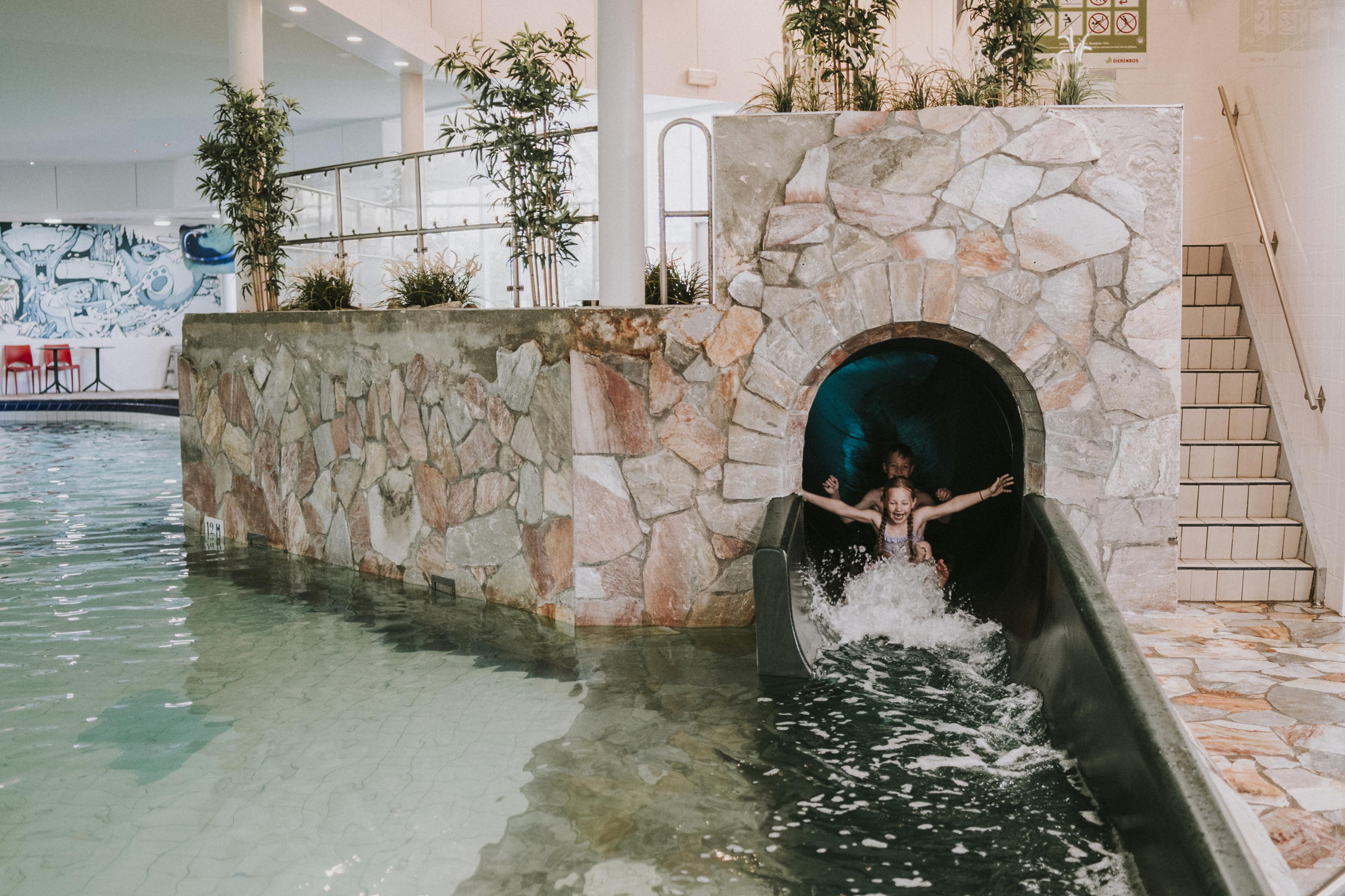 Kinderen gaan samen van de glijbaan in het zwembad van Vakantiepark Dierenbos