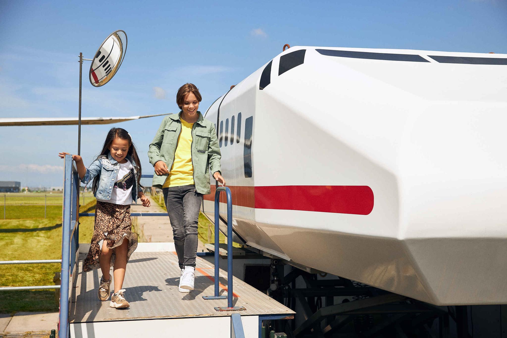 Een jongen en meisje bij de buiten vluchtsimulator van Luchtvaartmuseum Aviodrome.