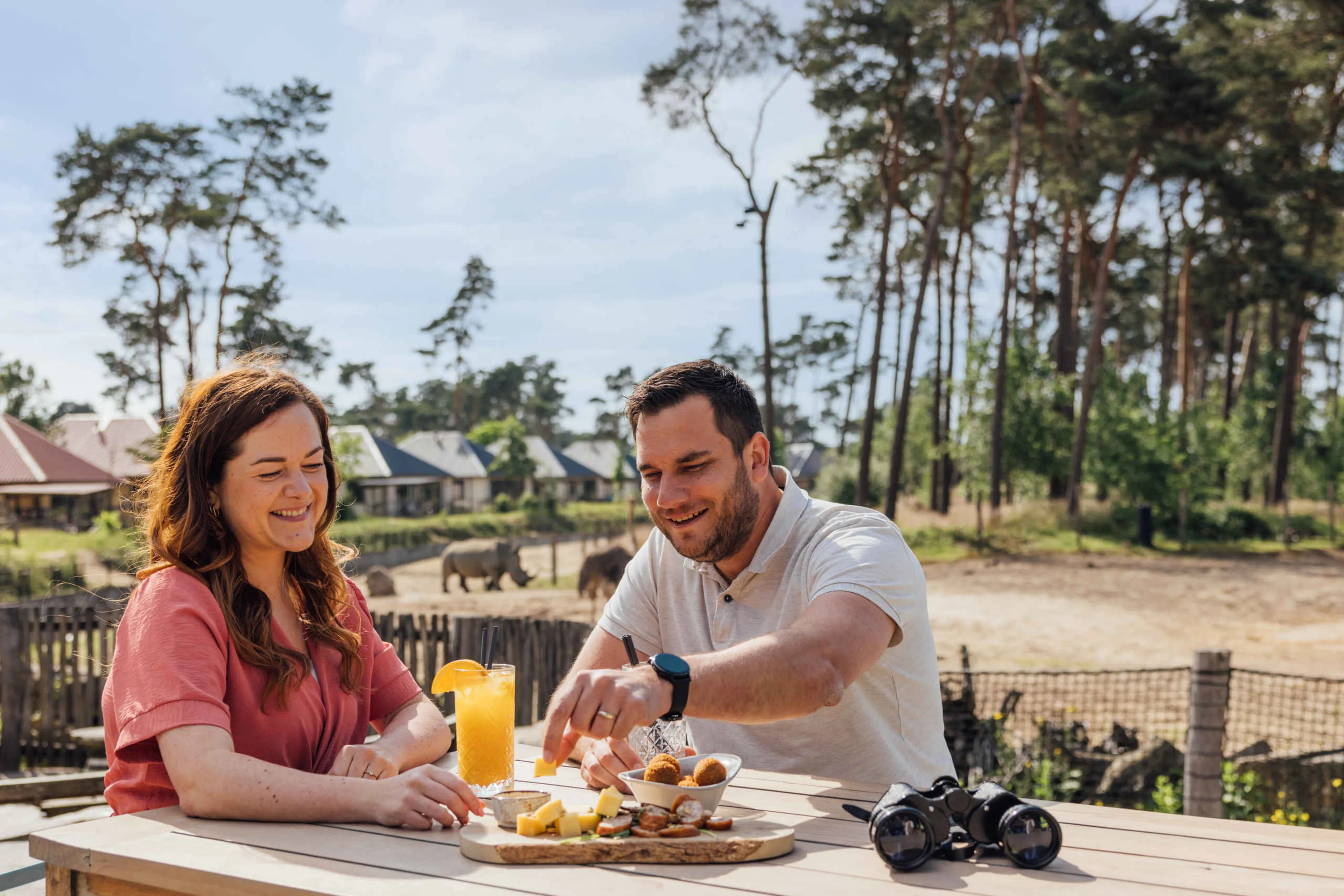 Een stel geniet van een borrelplank met uitzicht op de savanne bij restaurant Moto in Safari Resort Beekse Bergen