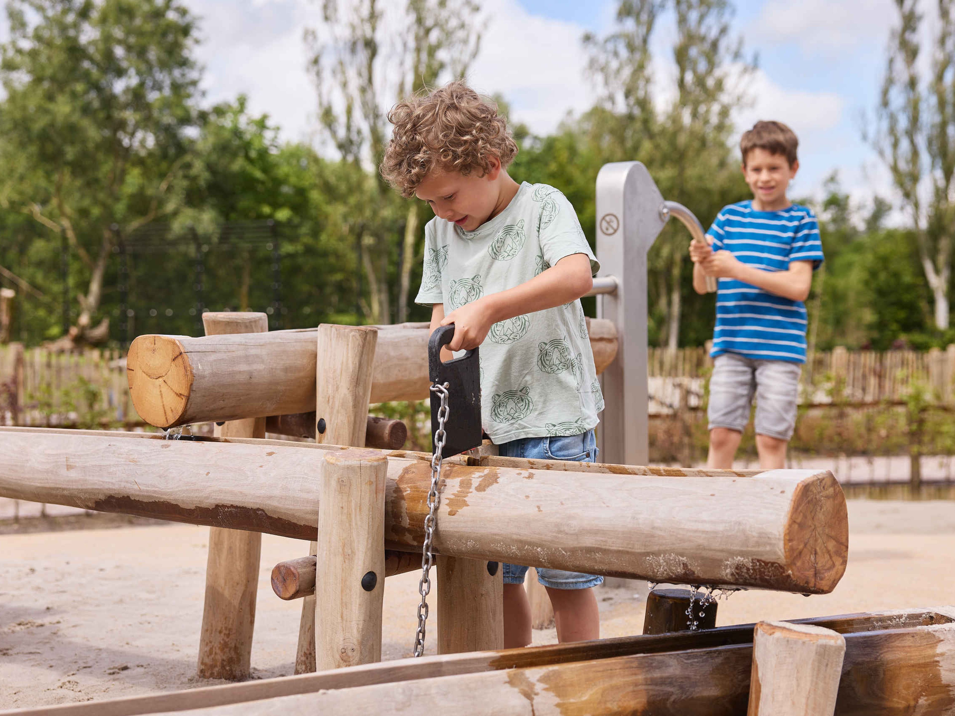 Twee kinderen spelen bij de waterpomp in de waterspeeltuin bij Eindhoven Zoo.