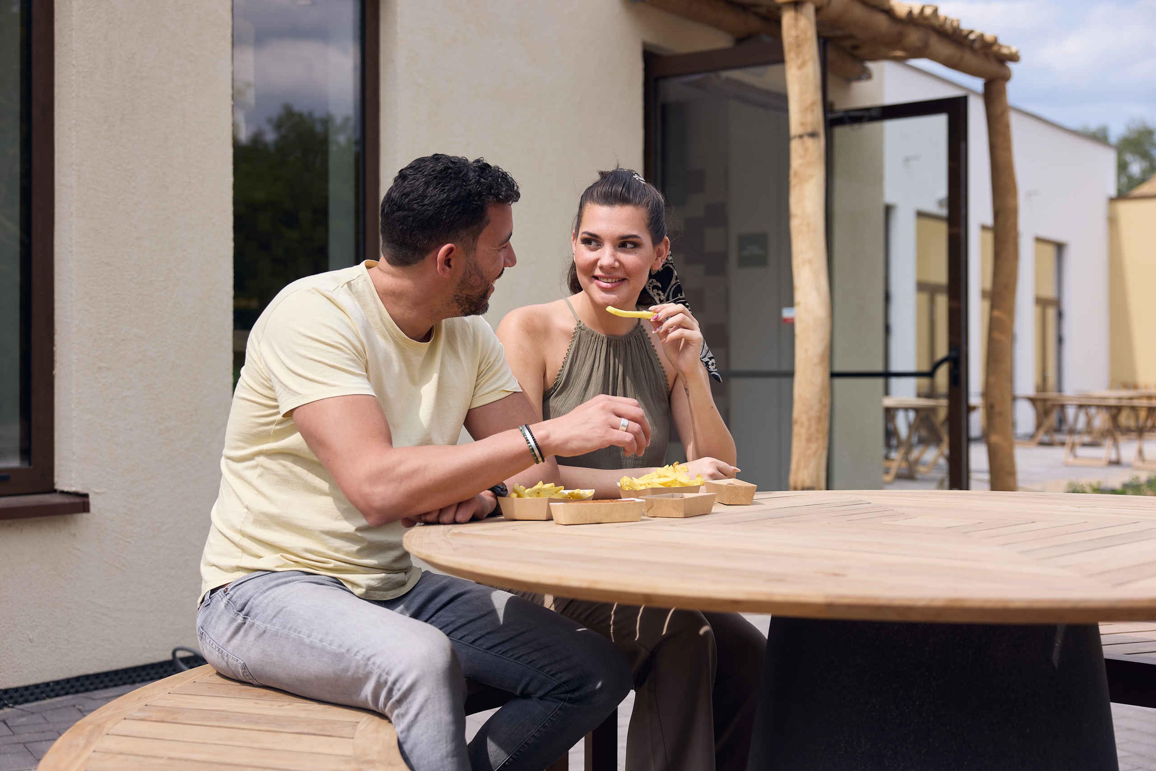 Een man en een vrouw eten frietjes bij snackbar Jaaba Counter bij Lake Resort Beekse Bergen.