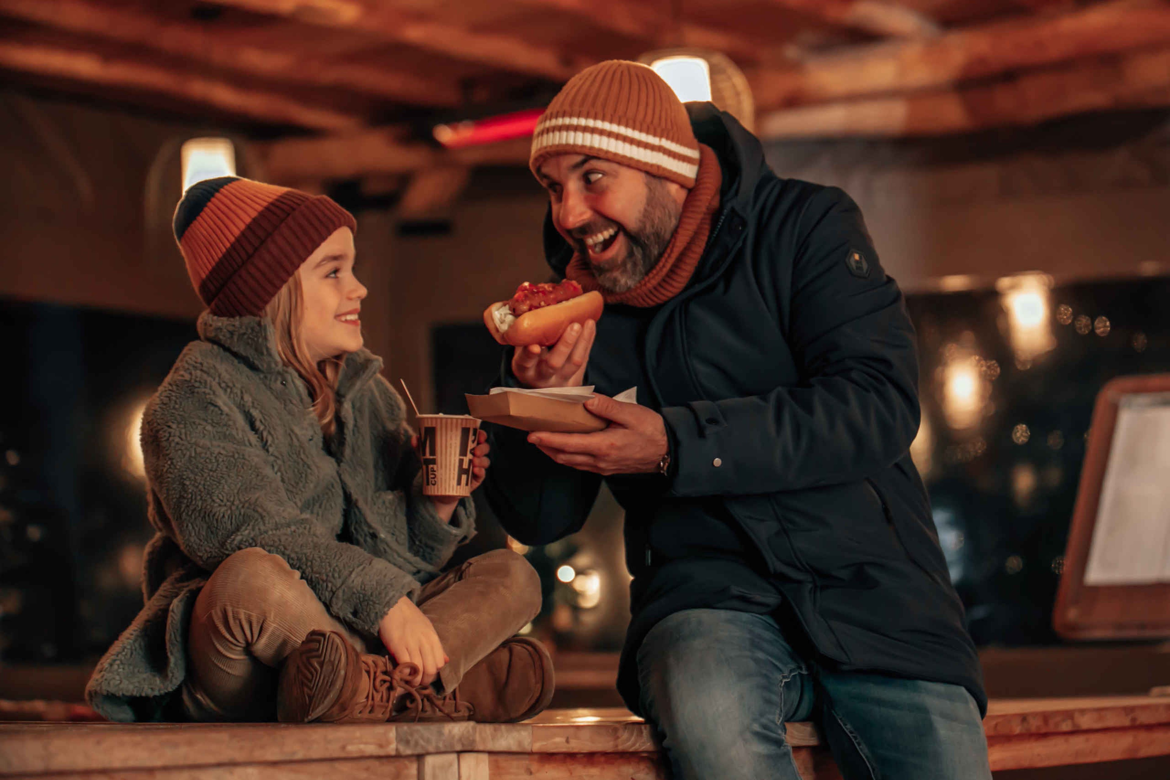 Een man en zijn dochter eten en drinken iets lekkers in de winter bij het Safari Resort Beekse Bergen.