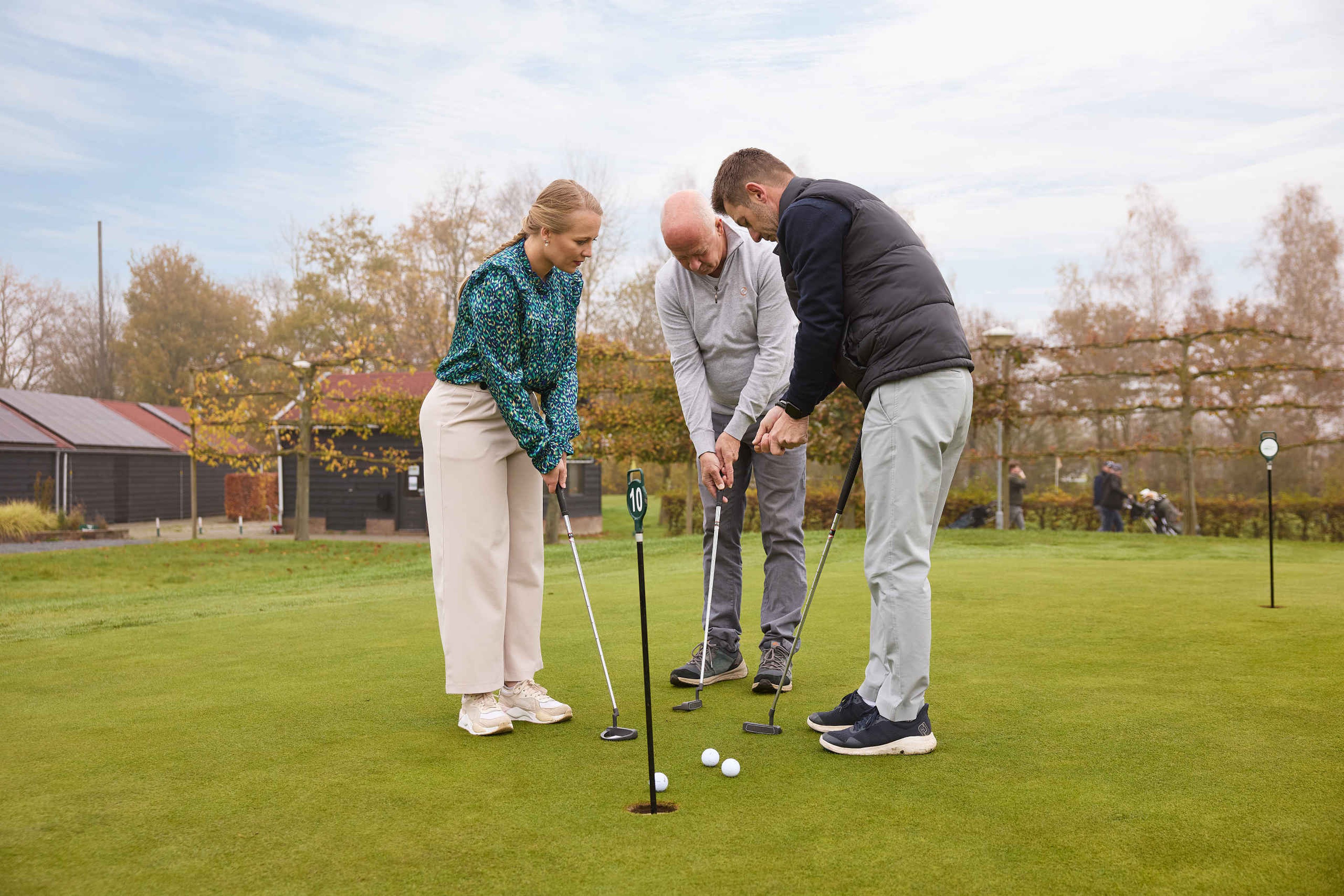 De golfpro met twee cursisten op de putting green bij Golf De Gulbergen