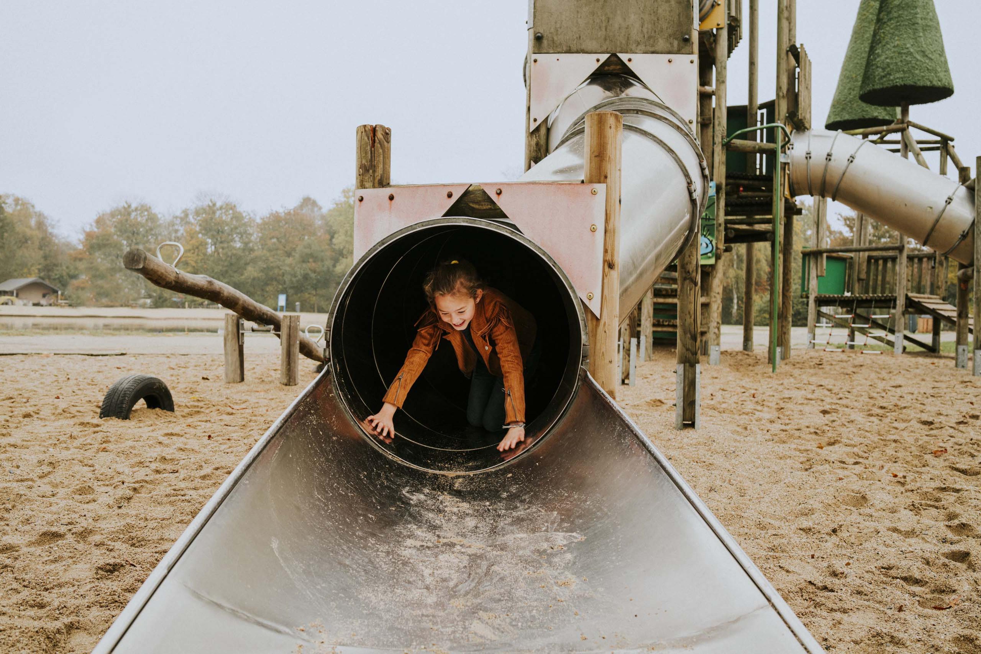 Kind op de glijbaan in de speeltuin van Vakantiepark Dierenbos