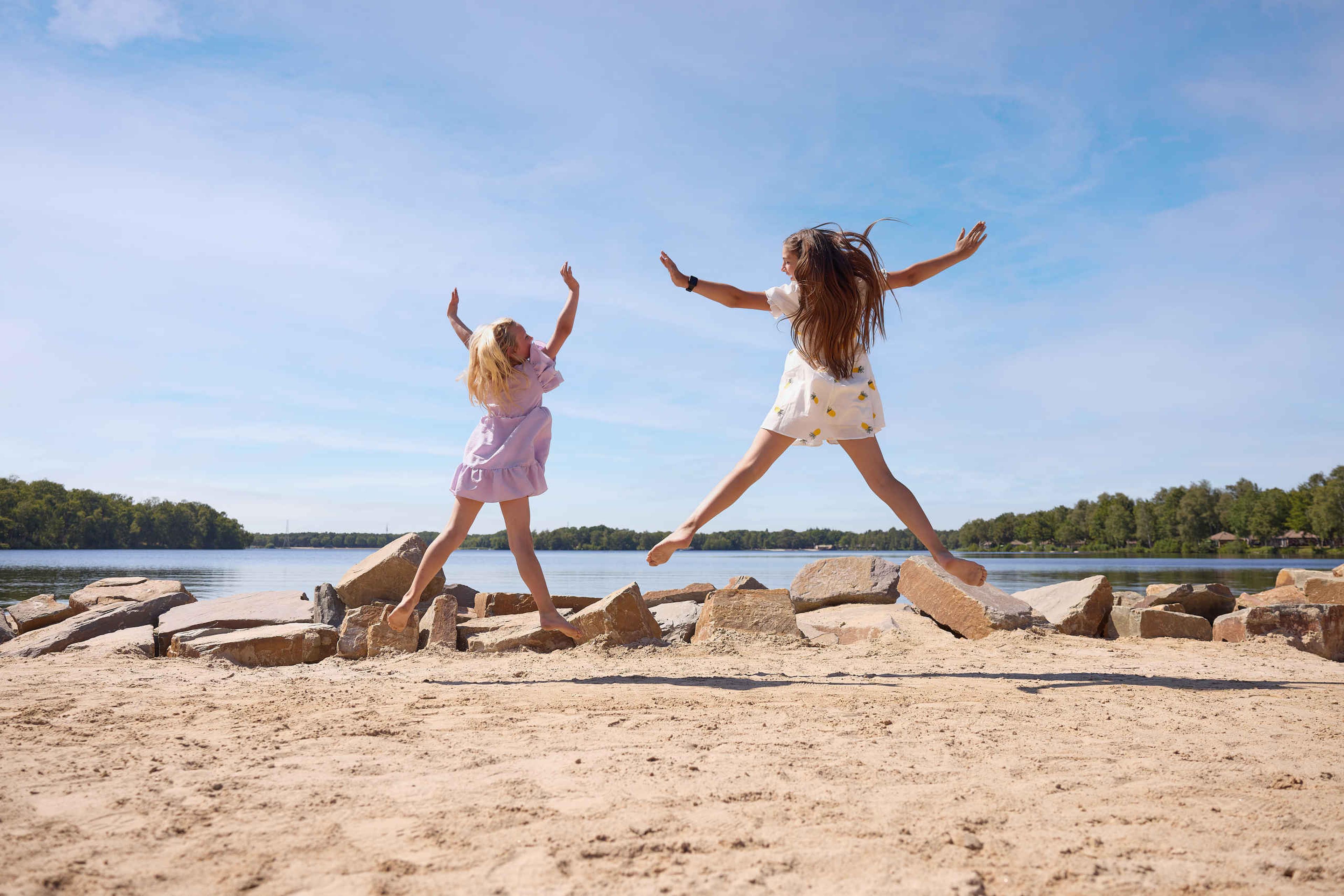 Kinderen springen in de lucht op het strand bij Lake Resort Beekse Bergen