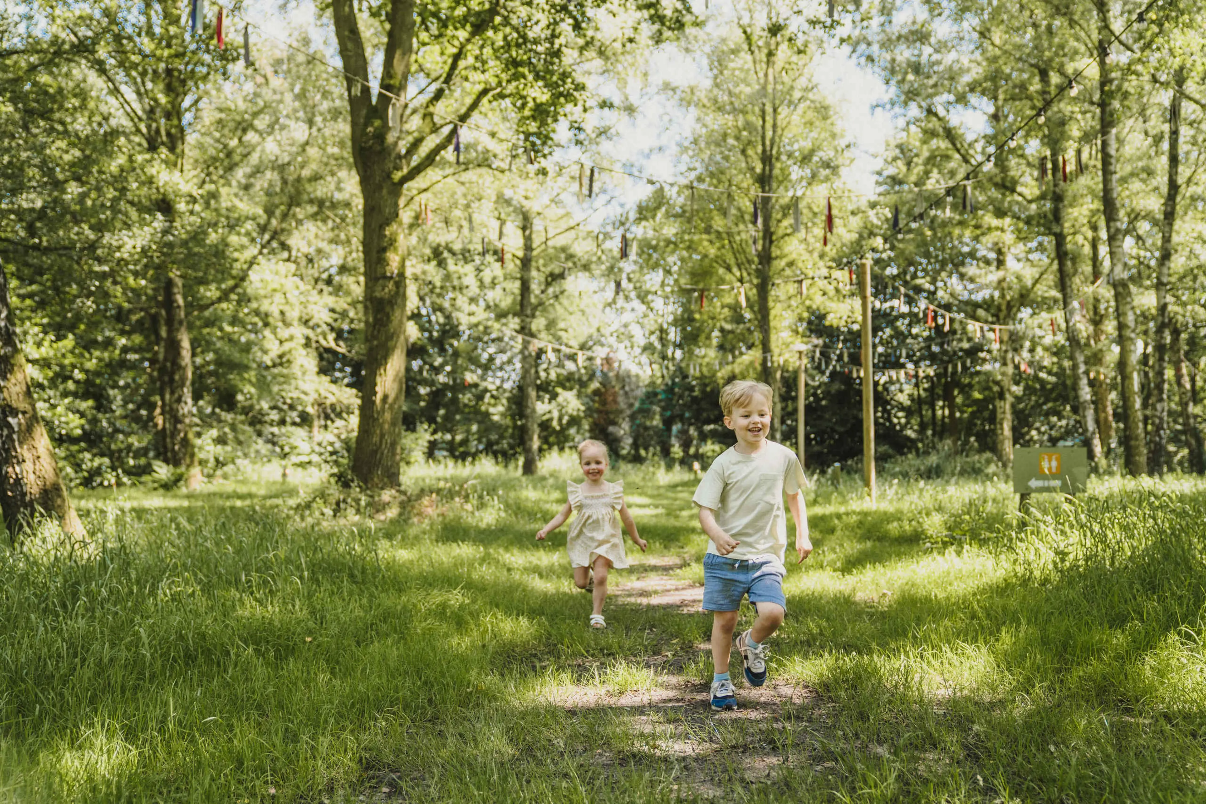 Twee kinderen rennen in het gras bij belevingscamping Vuurvlinder bij Vakantiepark Dierenbos