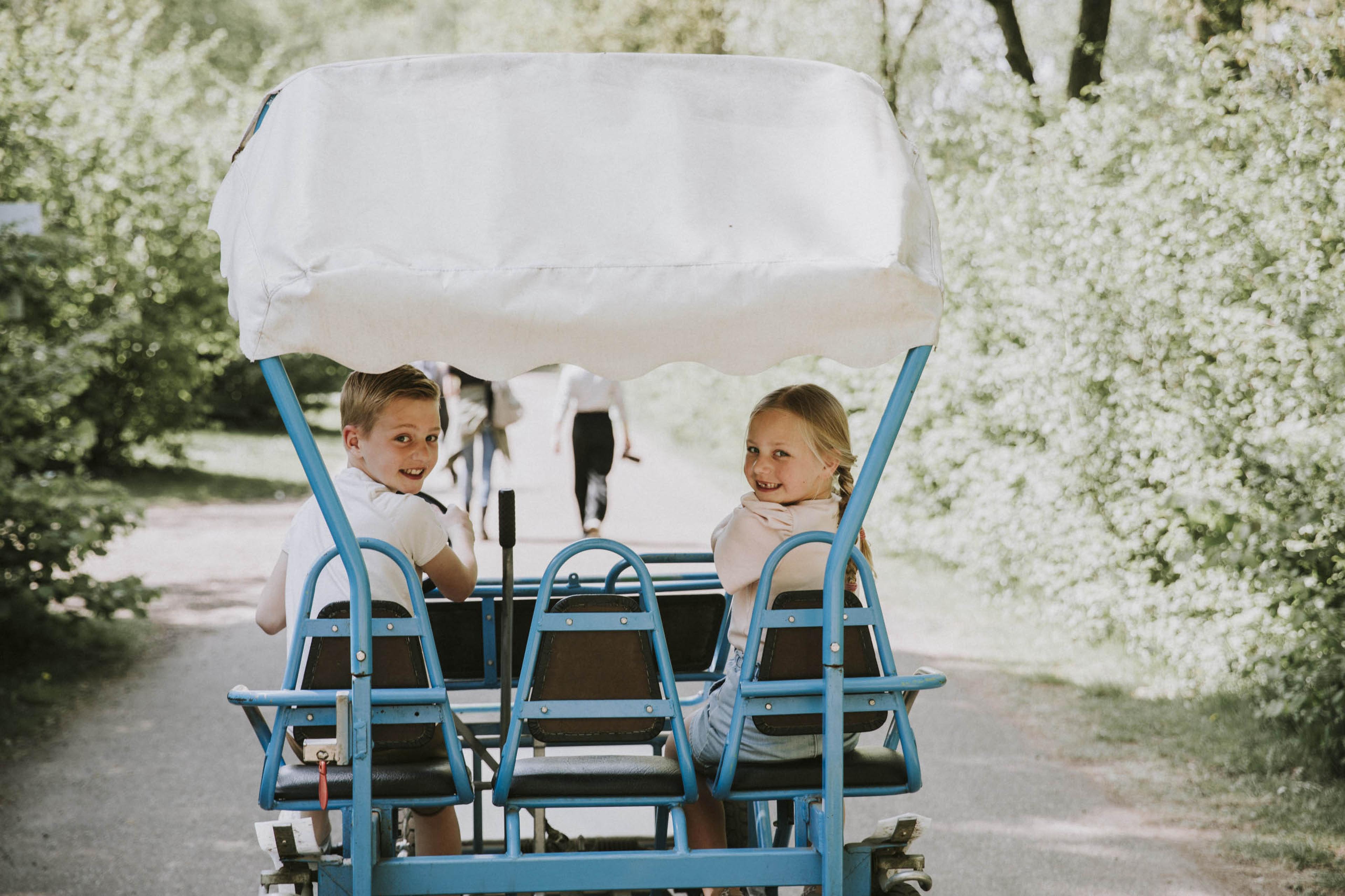 Kinderen kijken achterom op familiefiets van Vakantiepark Dierenbos