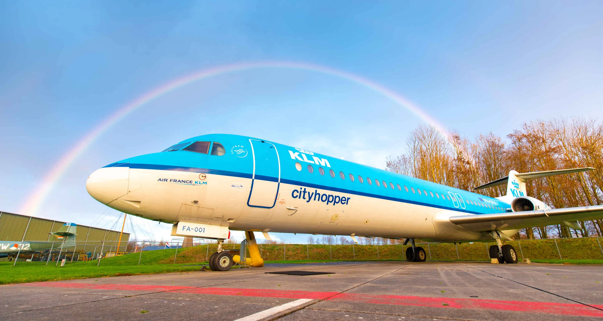 Een KLM cityhopper onder een regenboog op het buitenterrein van Luchtvaartmuseum Aviodrome